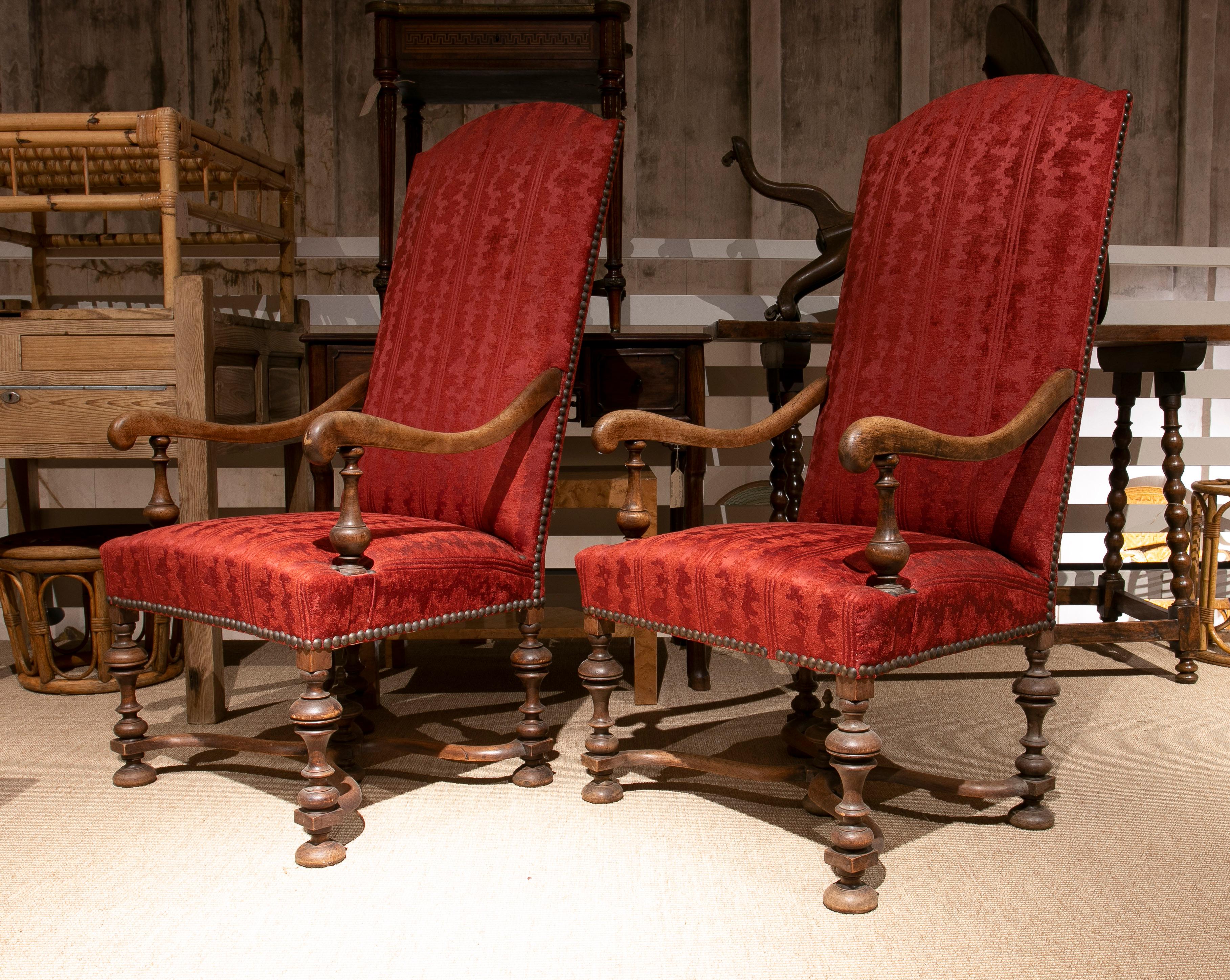 Pair of English wooden nailhead trim upholstered tall back armchairs with spindle legs and armrest supports.