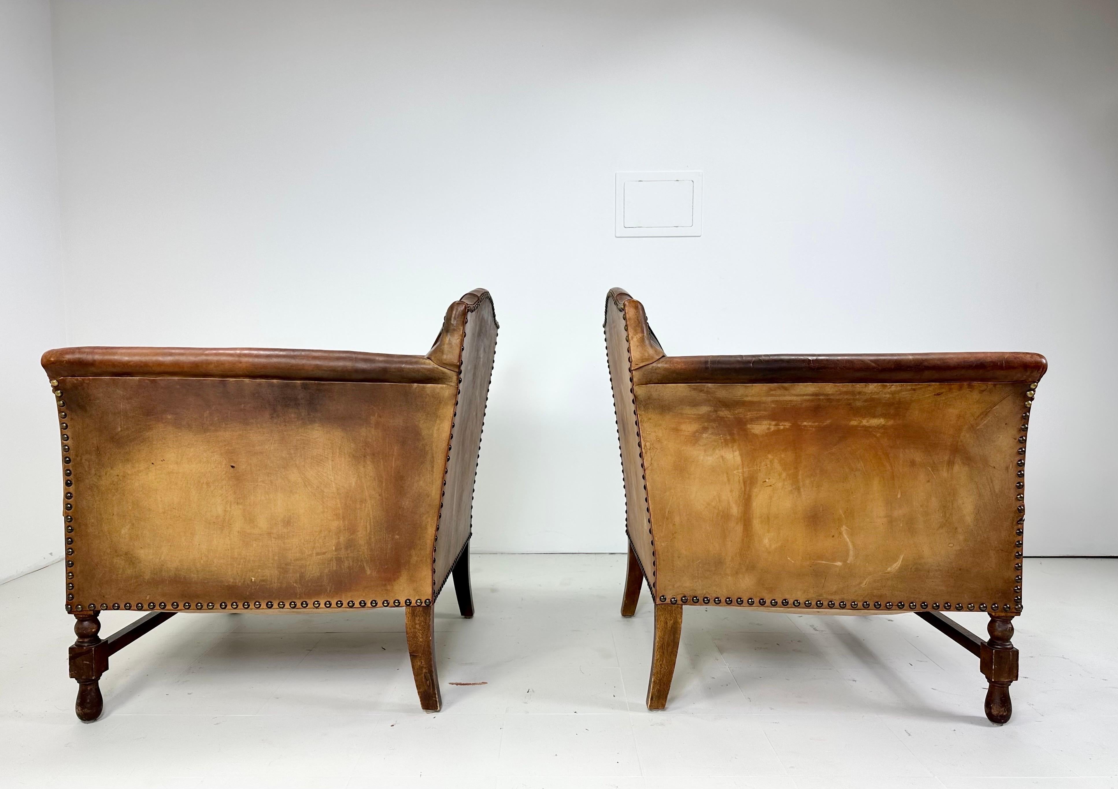 Early 20th Century European Leather Lounge Chairs. Decorative nailhead design. Turned wood legs. Later upholstery to seat cushion. Possible 1920's. Nicely worn leather patina.

Delivery to NYC Available for $425