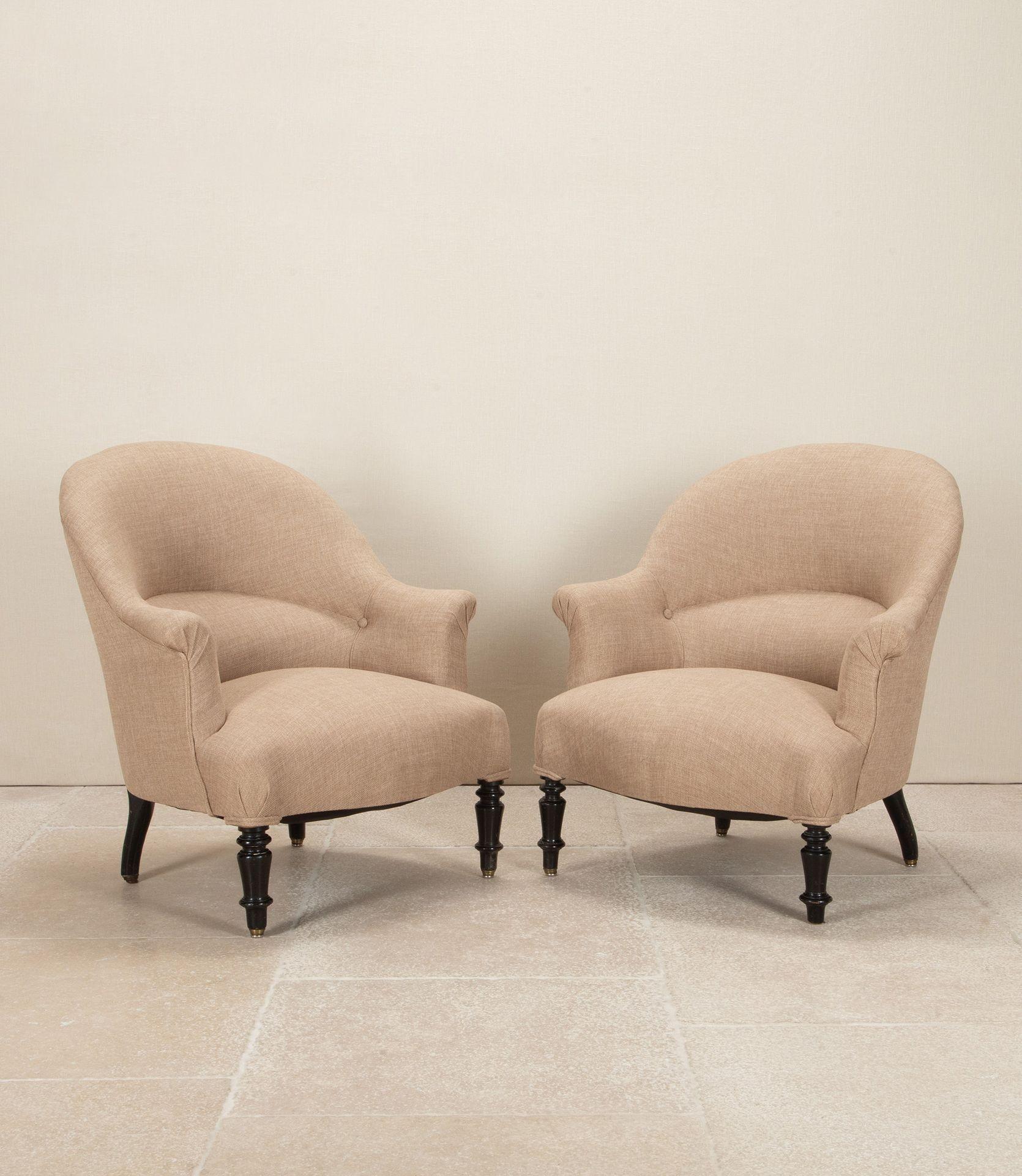 A pair of early 20th Century French armchairs.
Commonly referred to as 'crapaud chairs' on turned ebonised legs and castors. 
These chairs have been totally reupholstered in a neutral fabric.
Circa 1900.