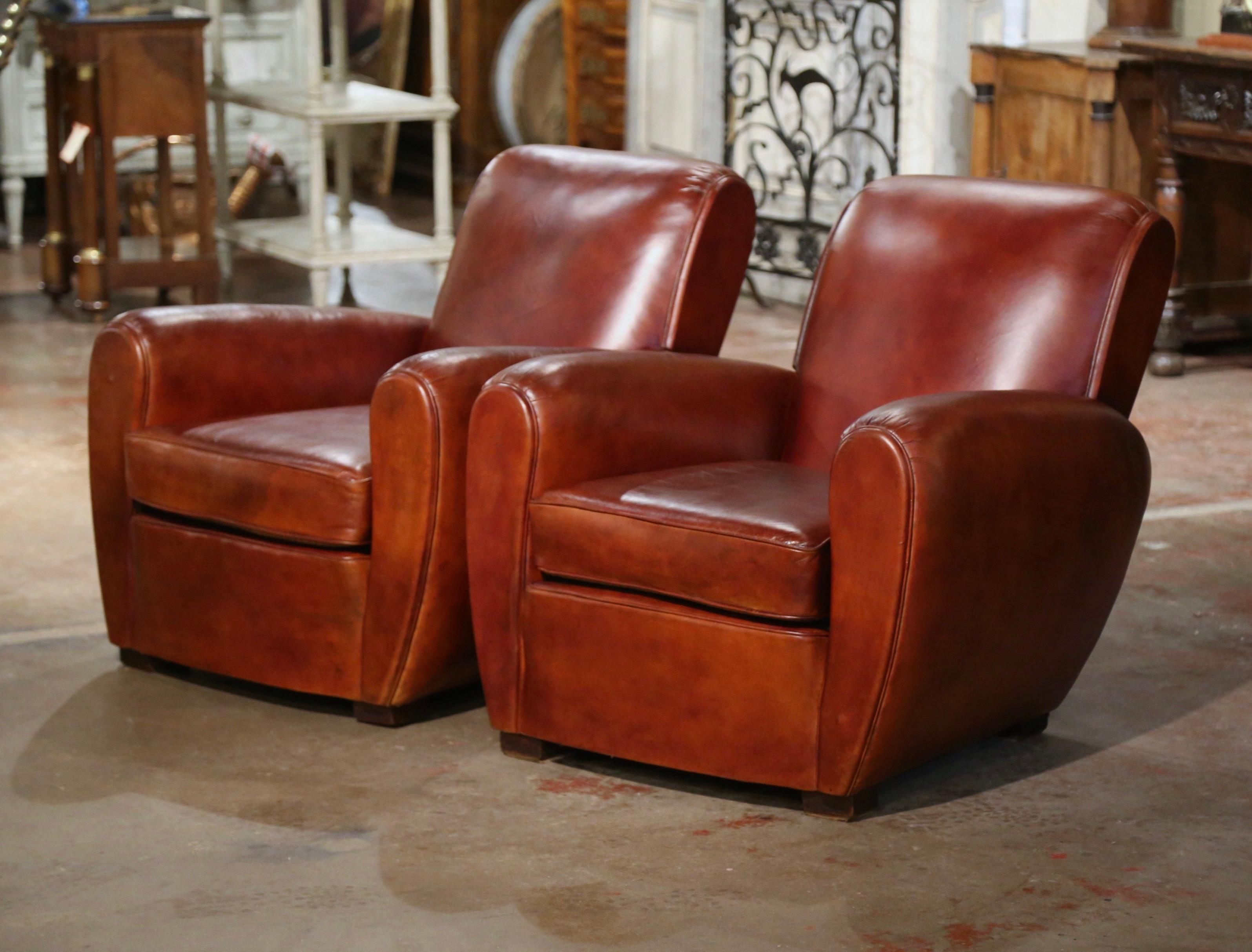 These classic, antique Art Deco club chairs were crafted in France, circa 1920. The stately chairs sit on square feet, and feature wide, elegant rounded armrests, over a pitched square back. The Classic, masculine French chairs are upholstered with