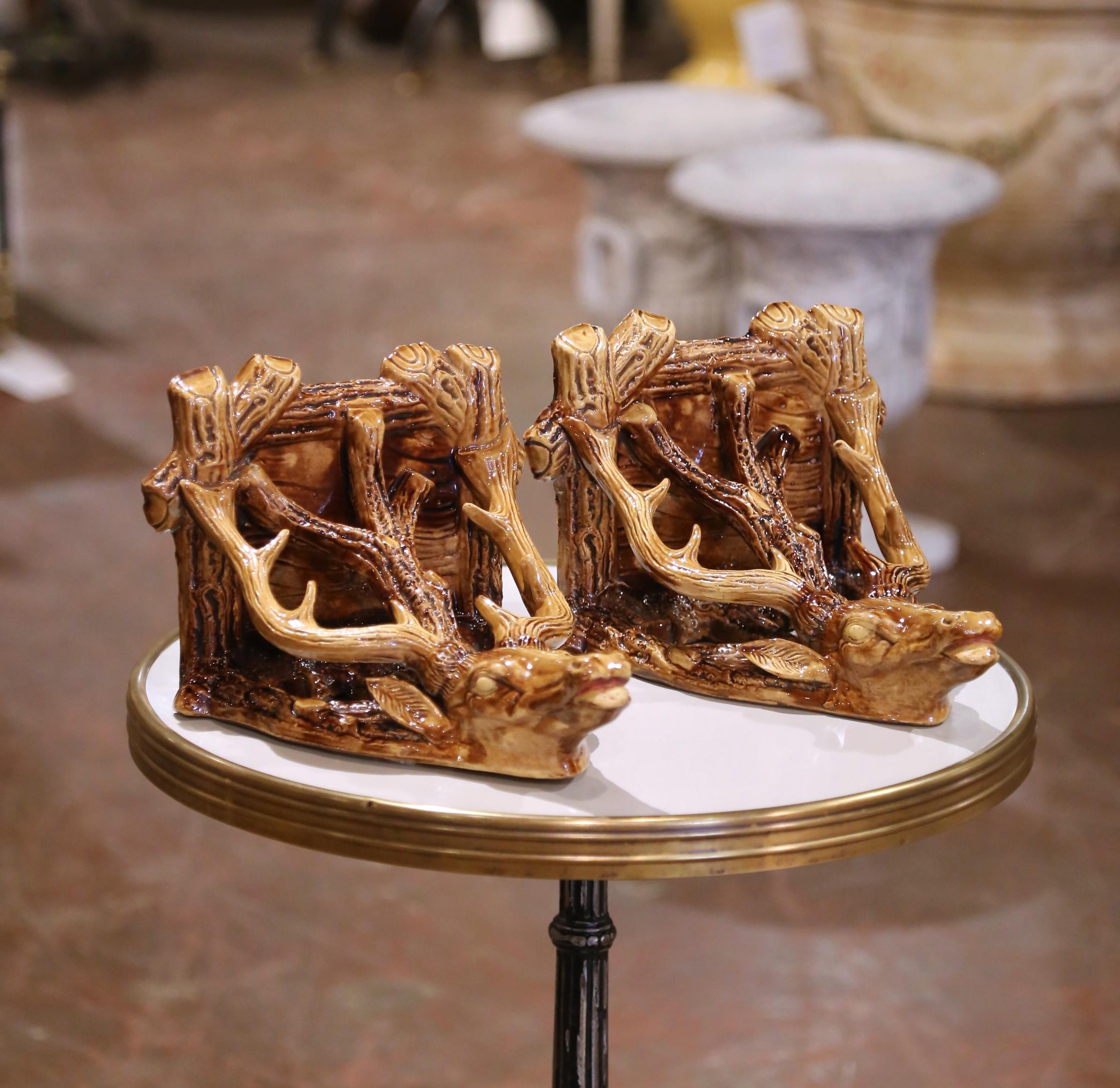 Questa straordinaria coppia di mensole antiche da parete è stata realizzata in Francia intorno al 1920 in ceramica Barbotine riccamente smaltata. Ogni staffa è caratterizzata da una testa di cervo rosso scultorea con corna elaborate che formano un