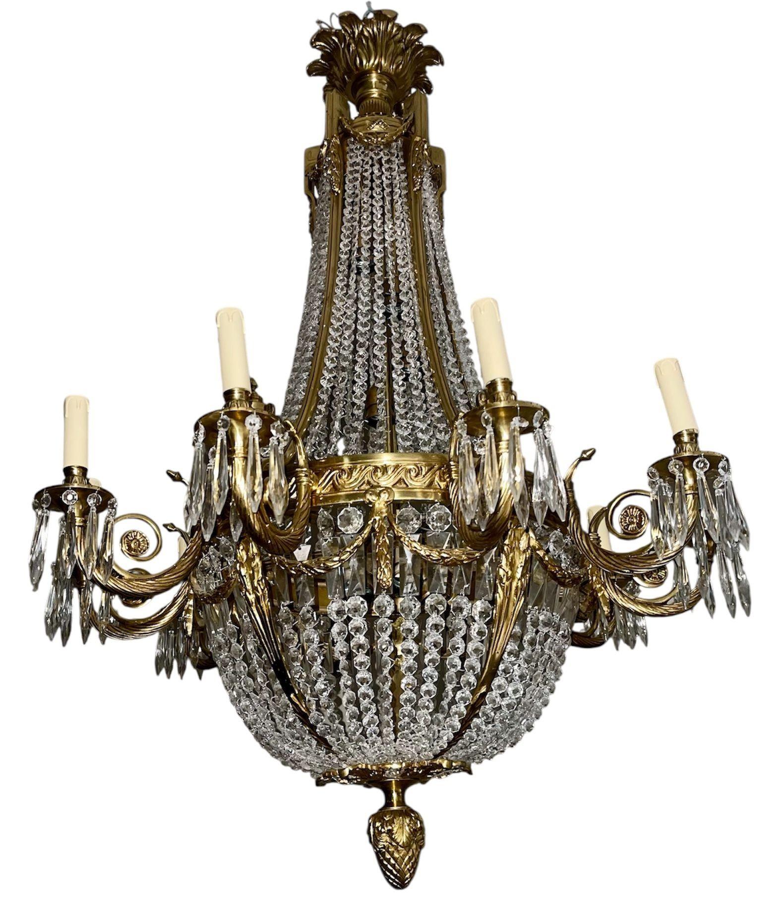 Superbe paire de lustres français du début du 20e siècle, en bronze doré et drapés de perles de cristal finement taillées, dans le style d'un panier. Le lustre présente des bras en bronze à volutes avec des lumières en forme de bougie, ornées de
