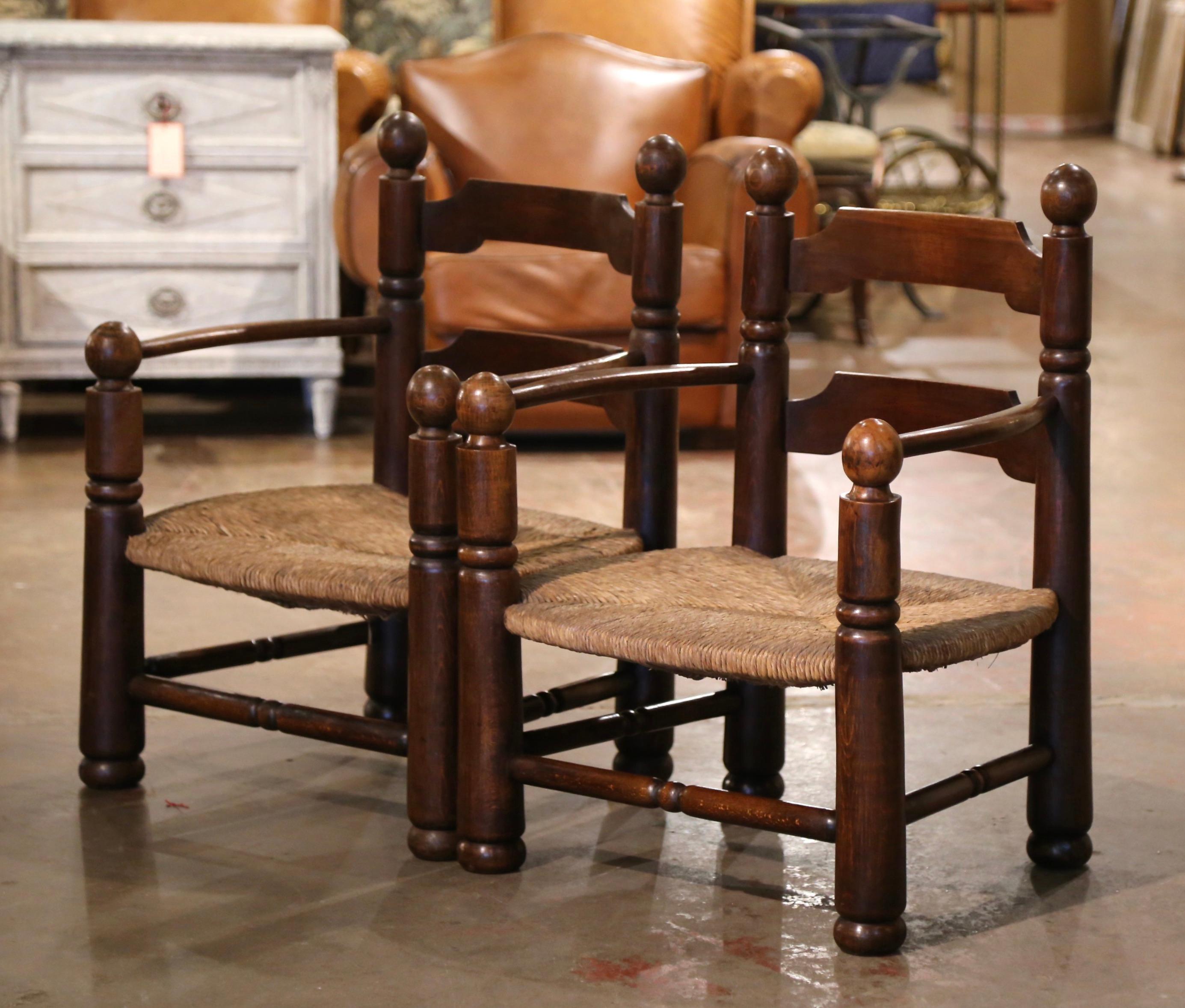 These very comfortable antique ladder back chairs with armrests were crafted in Normandy, France circa 1920. Built in oak and beechwood and attributed to Charles Dudouyt, each armchair sits on round turned legs and features two ladders in the back