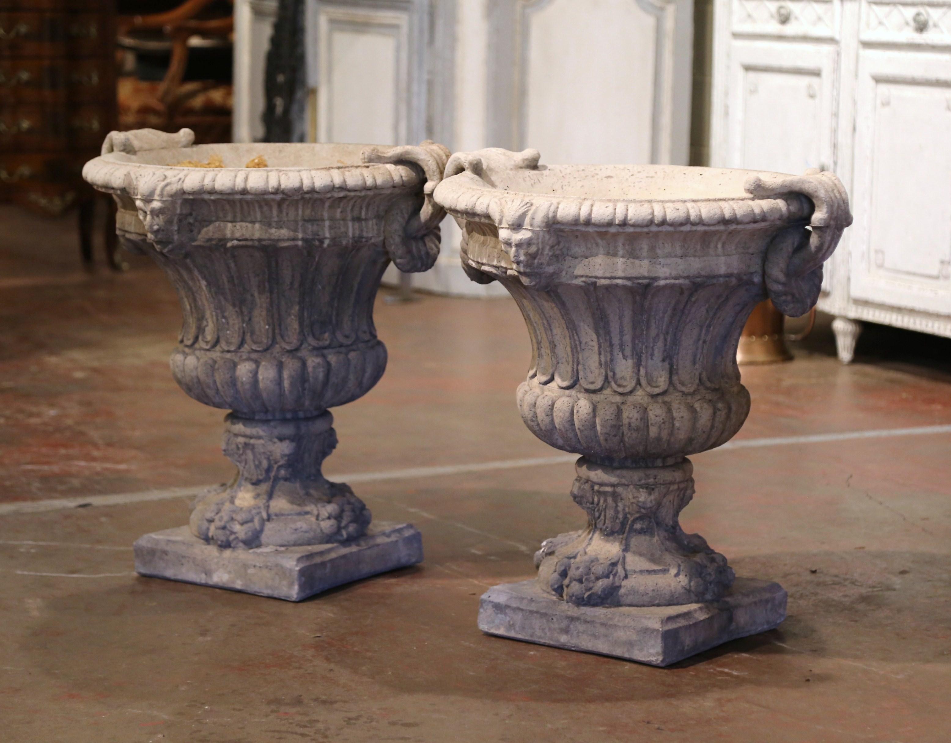 Decorate a patio with this elegant pair of antique outdoor planters. Carved in France, circa 1920, each stone jardinière stands on a square base over a short pedestal, and dressed with side ring handles and figural masks; the neoclassical urn has a