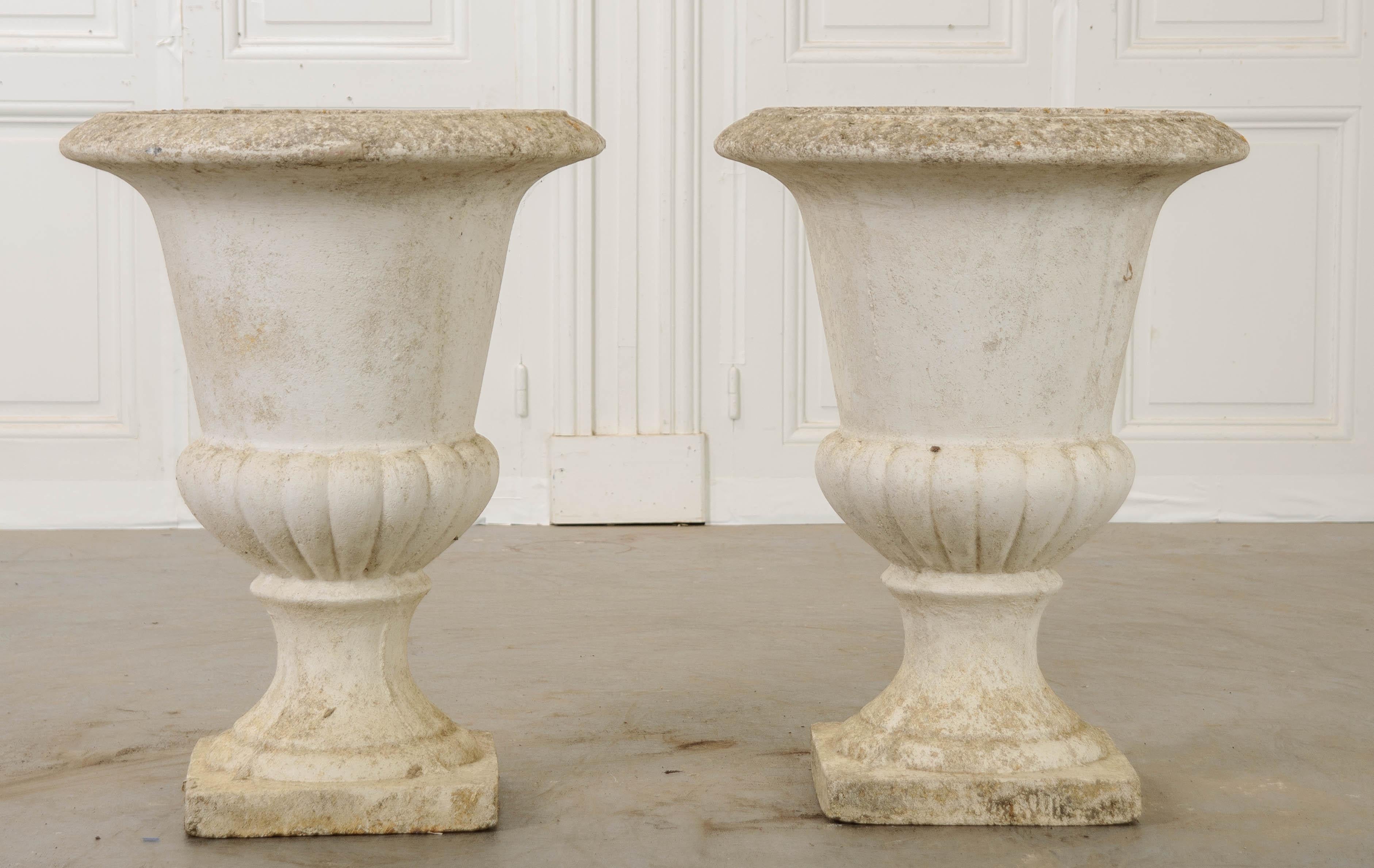 A handsome pair of urn-form planters, made of cast stone and painted white. Dating to 1900s France, the pair have an aged appearance that is not only incredible, but genuine. The planters’ lips have been styled with an egg and dart motif that has