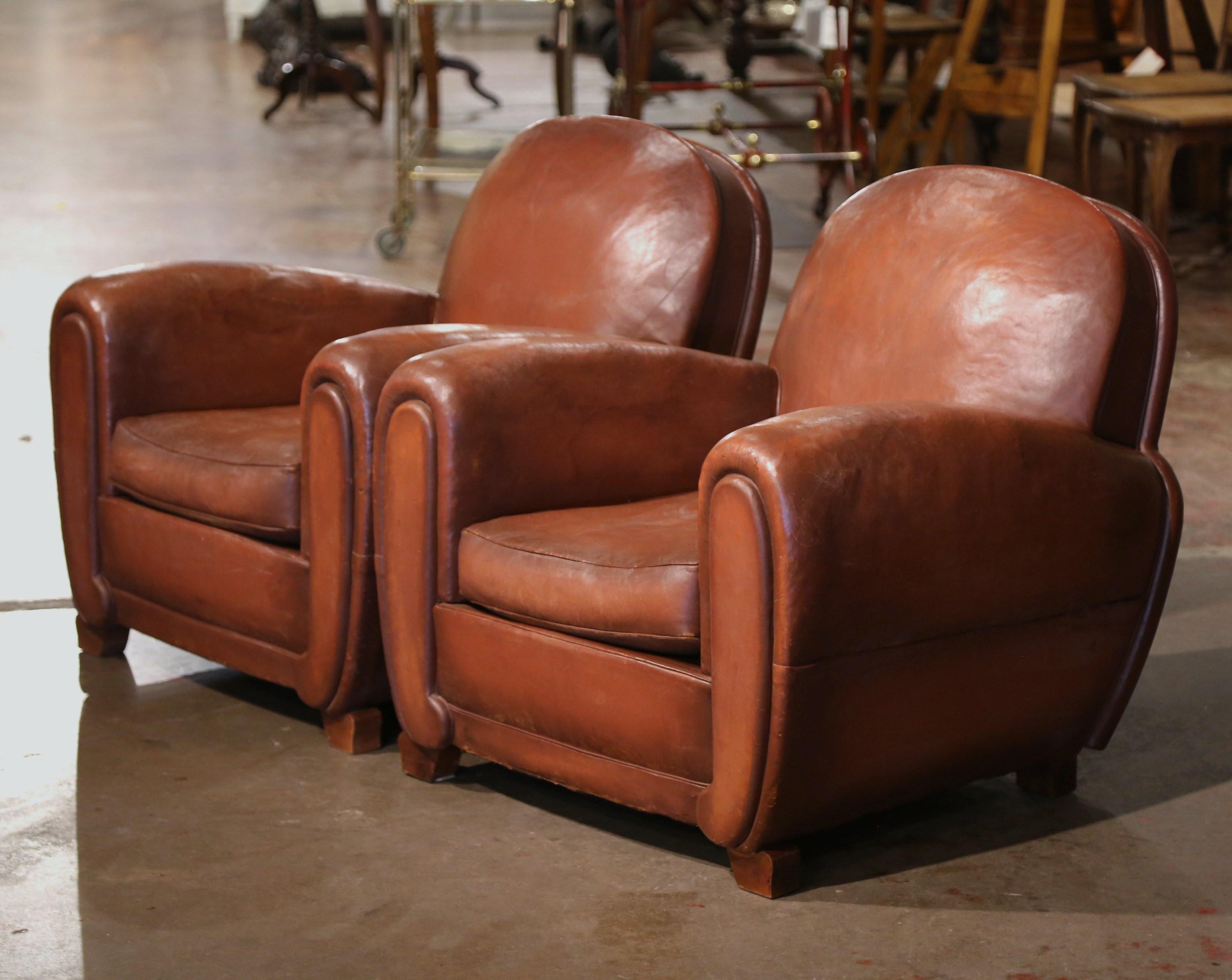 These classic, antique Art Deco club chairs were crafted in France, circa 1920. The stately chairs sit on square feet, and feature wide, rounded armrests, over an arched back. The Classic, masculine French chairs are upholstered with their original