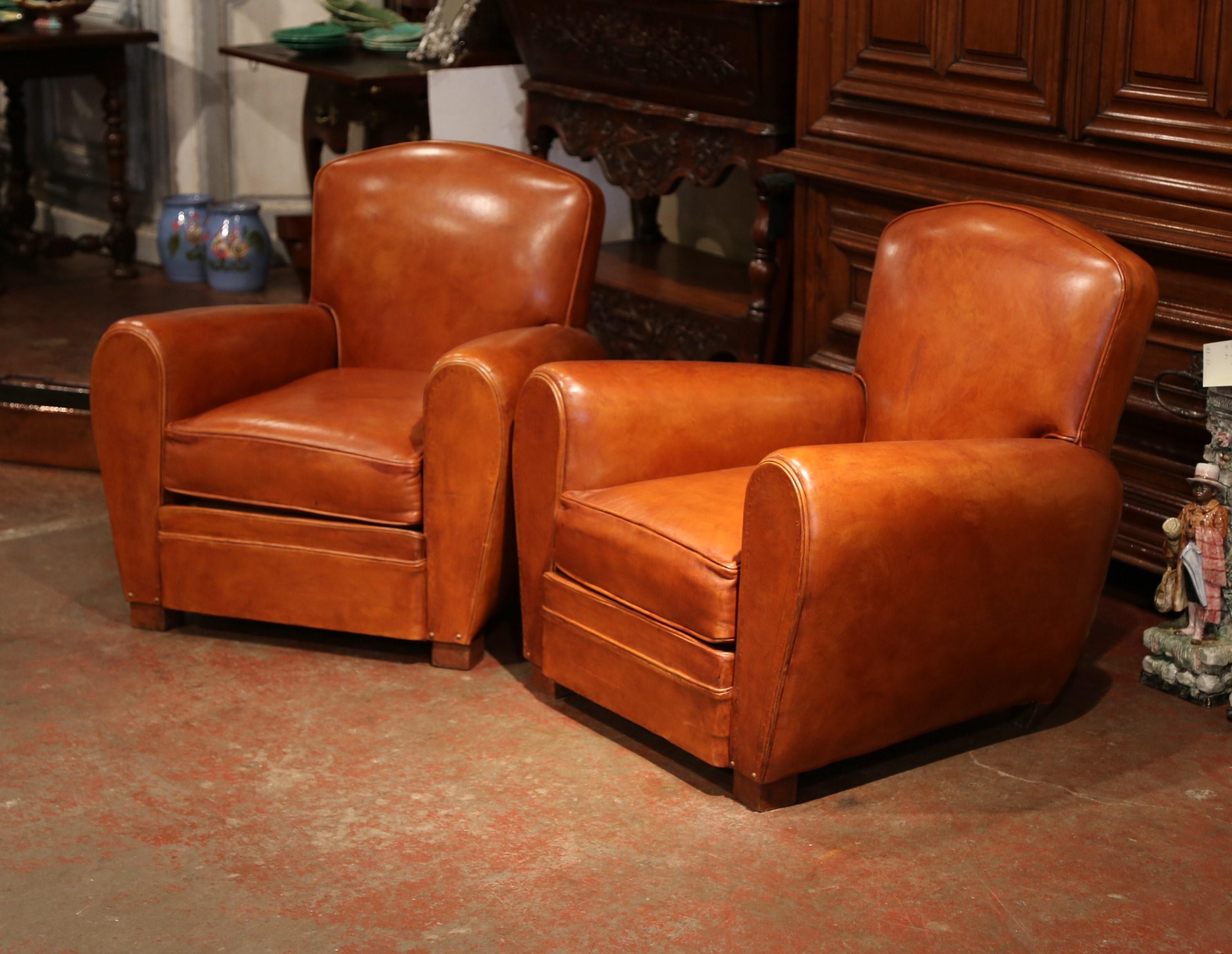 These Classic, antique Art Deco club chairs were crafted in France, circa 1920. The stately, masculine chairs feature wide, rounded armrests, a pitch back with an arched top shape, and square wooden feet at the base. The Classic, masculine French