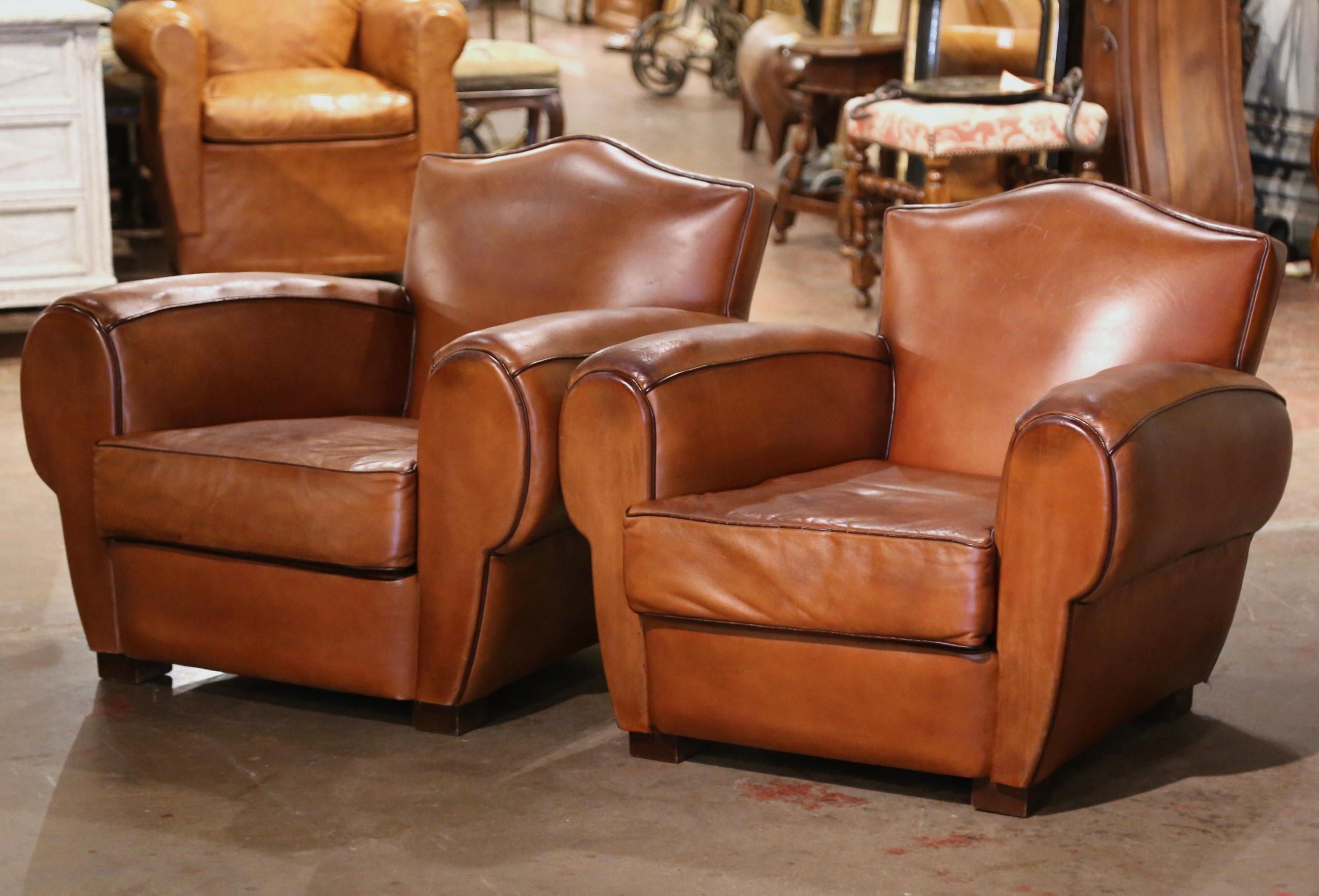 These Classic, antique Art Deco club chairs were crafted in France, circa 1920. The stately chairs feature wide, rounded armrests, a pitch back with an arched top shape, and square wooden feet at the base. The Classic, masculine French chairs with