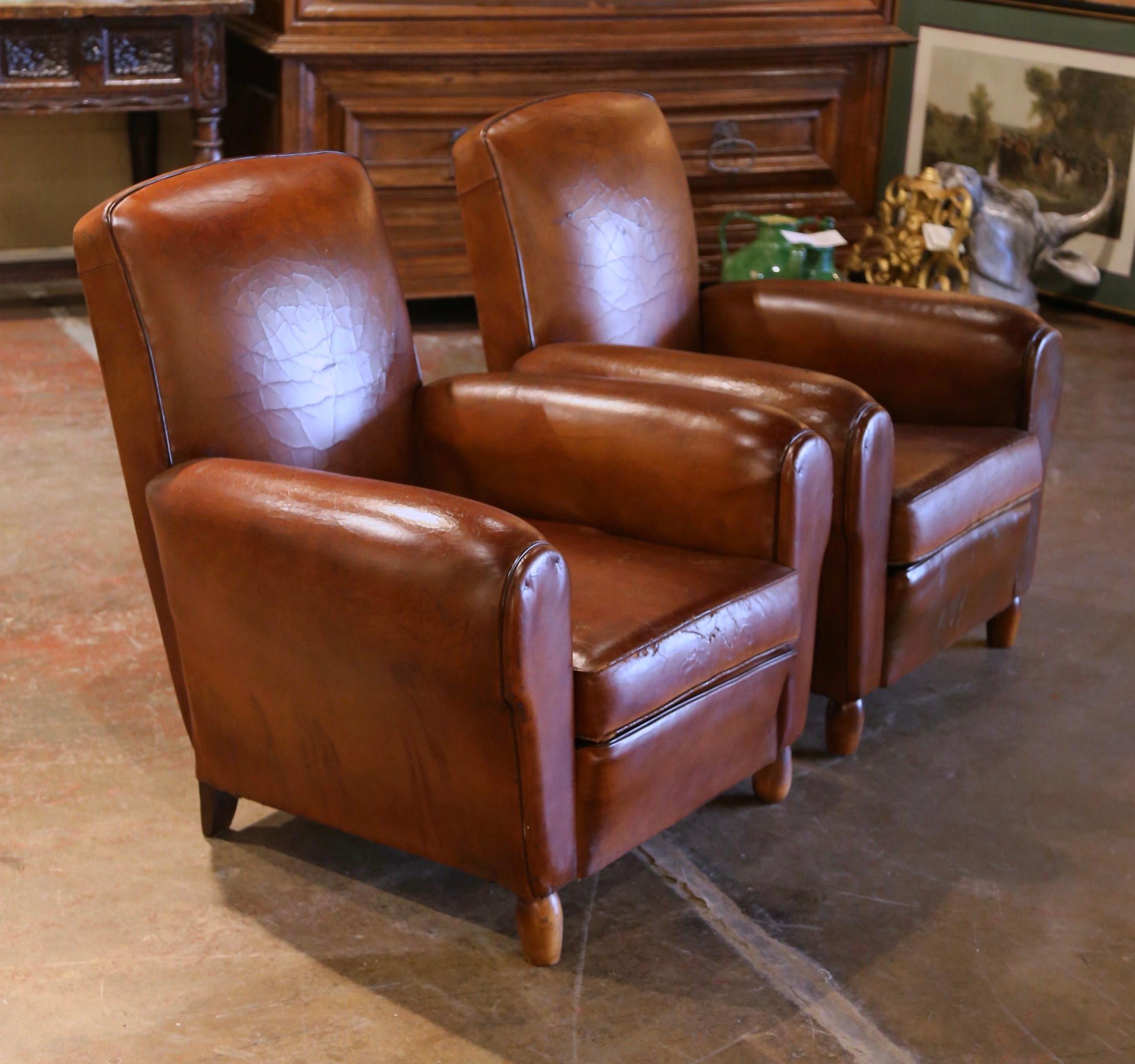 These Classic, antique Art Deco club chairs were crafted in France, circa 1920. The stately chairs stand on round wooden feet and feature wide, rounded armrests, a pitch back with an arched top shape. The Classic, masculine French fauteuils with