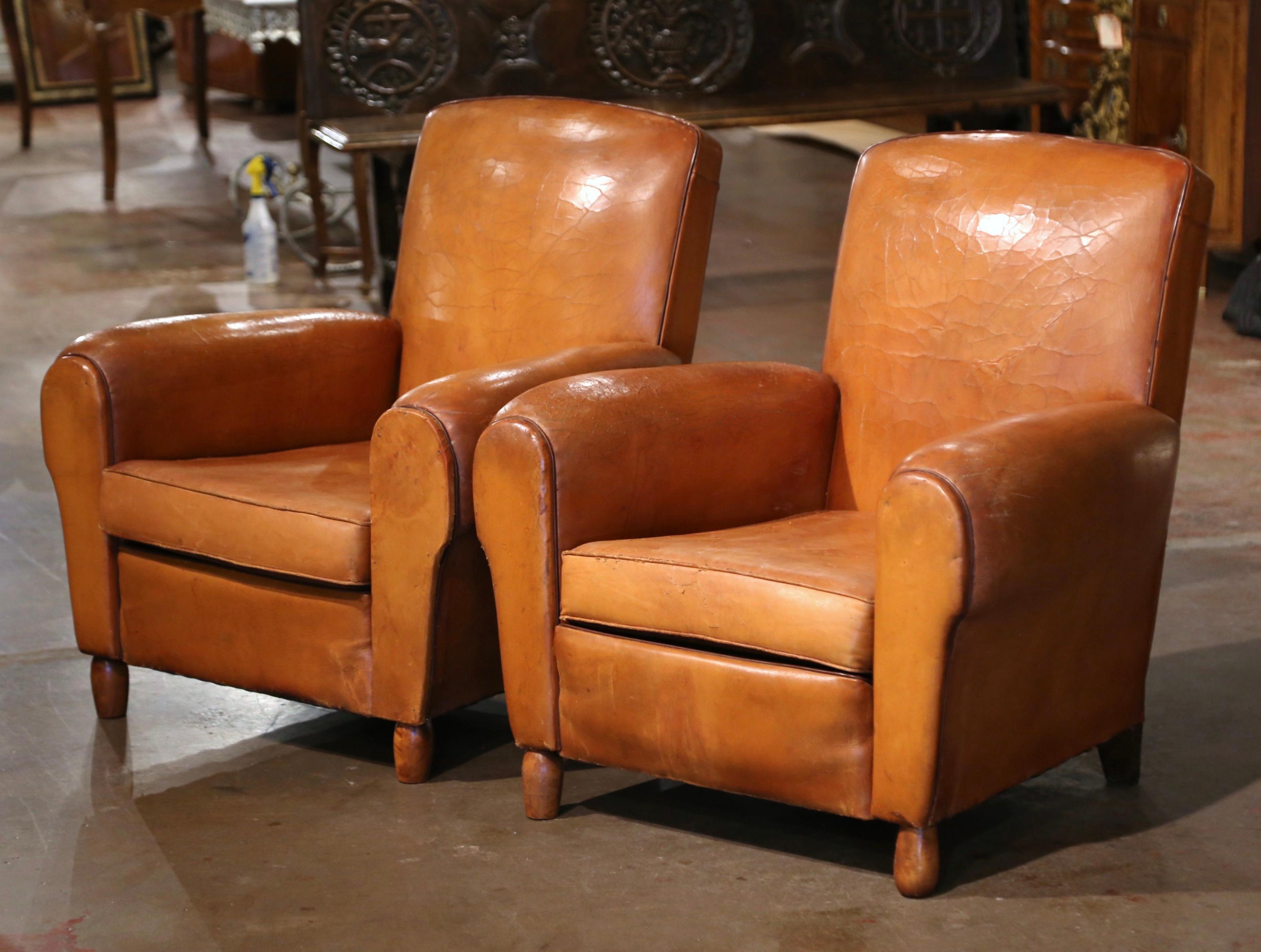 These Classic, antique Art Deco club chairs were crafted in France, circa 1920. The stately chairs stand on round wooden feet and feature wide, rounded armrests, a pitch back with an arched top shape. The Classic, masculine French fauteuils with