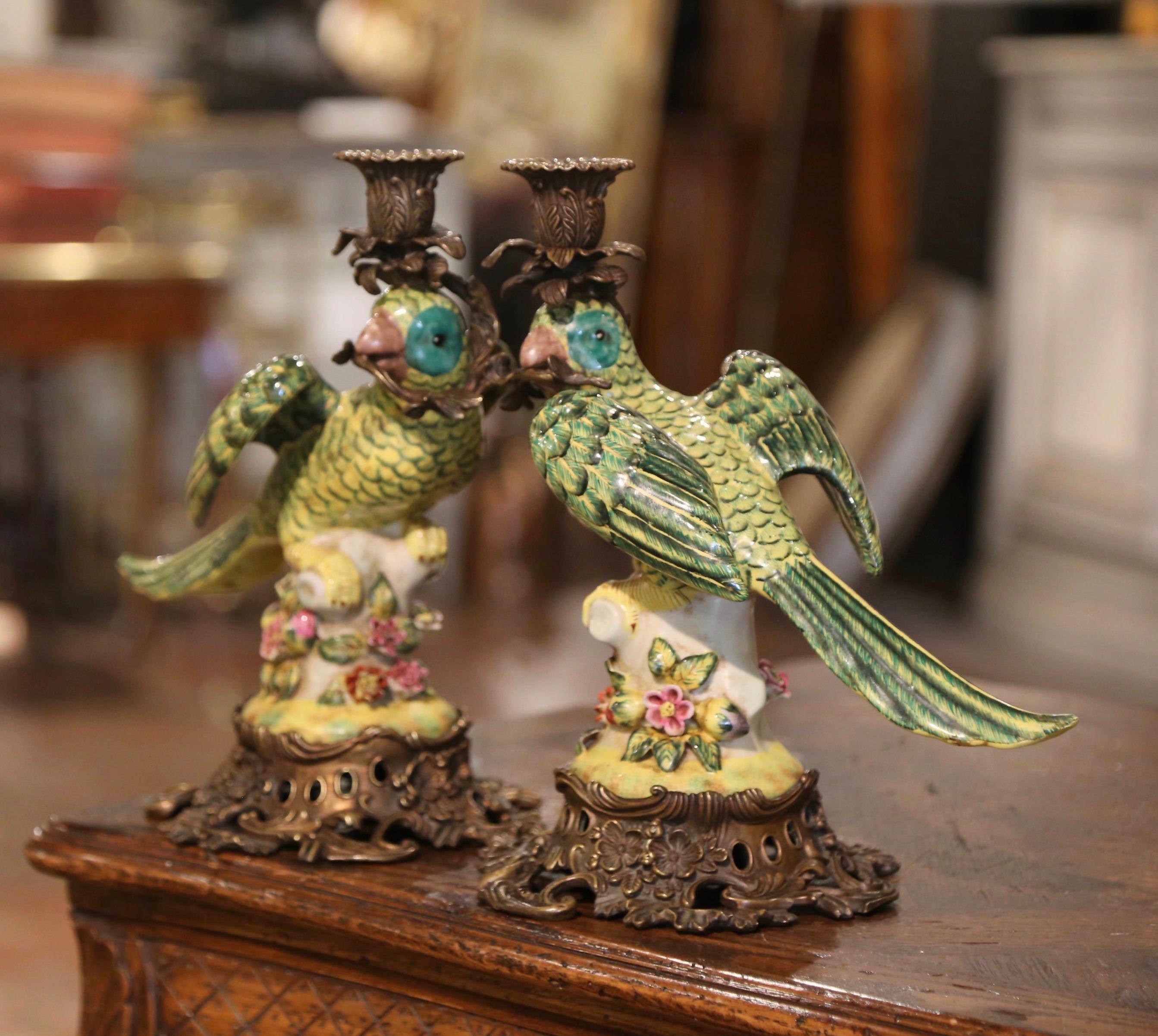 Decora una mensola con questa colorata coppia di sculture di uccelli. Realizzata in Francia intorno al 1920, ogni scultura poggia su una base in bronzo dorato decorata con motivi di foglie e conchiglie su piedini a voluta. L'uccello dipinto a mano
