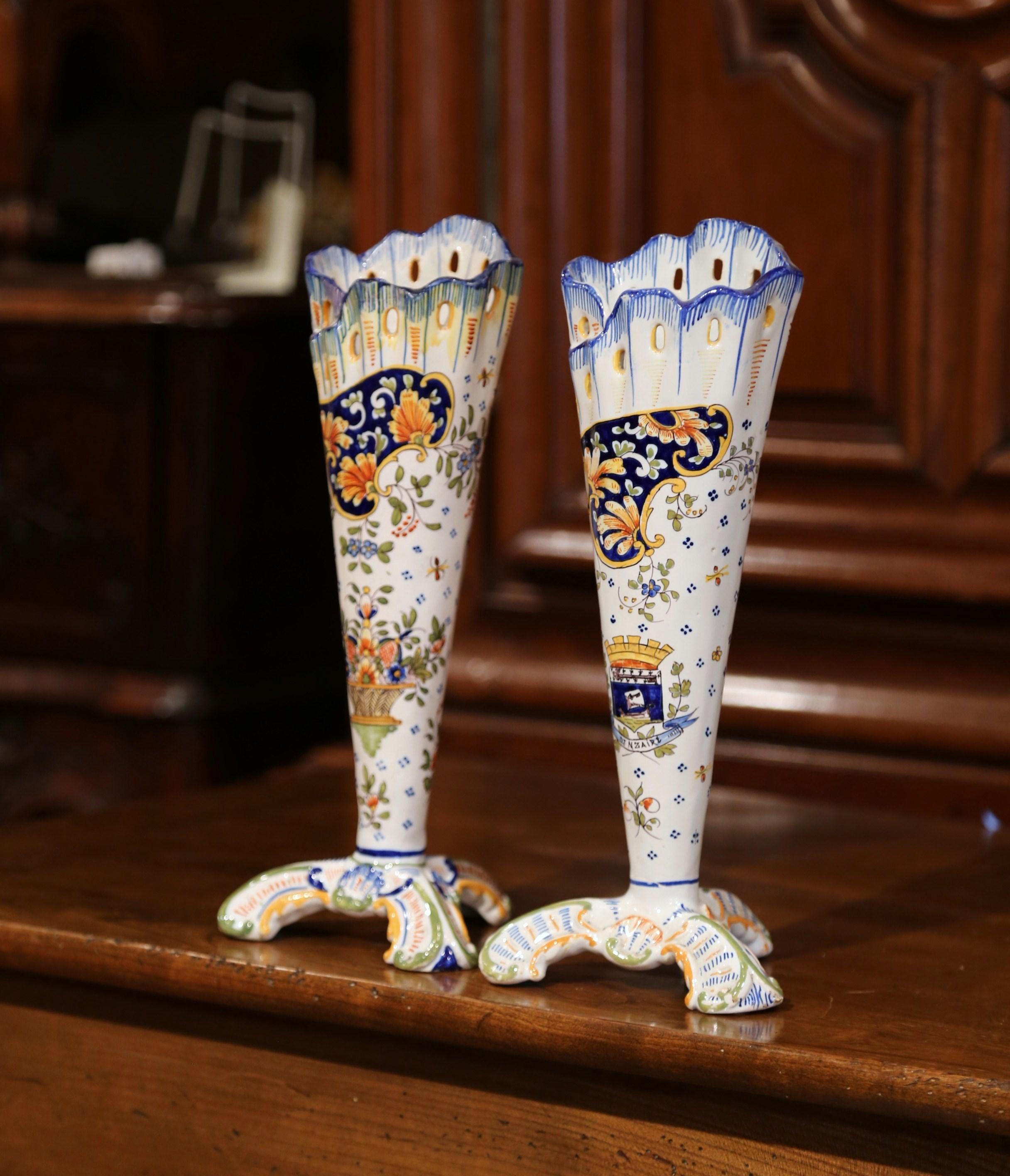 Incorporate beautiful colors into your home with this elegant pair of antique ceramic vases. Crafted in Normandy, France, circa 1920, the fluted vases sit on three legs and are ornate in decoration yet simple in shape. The tall, colorful vases