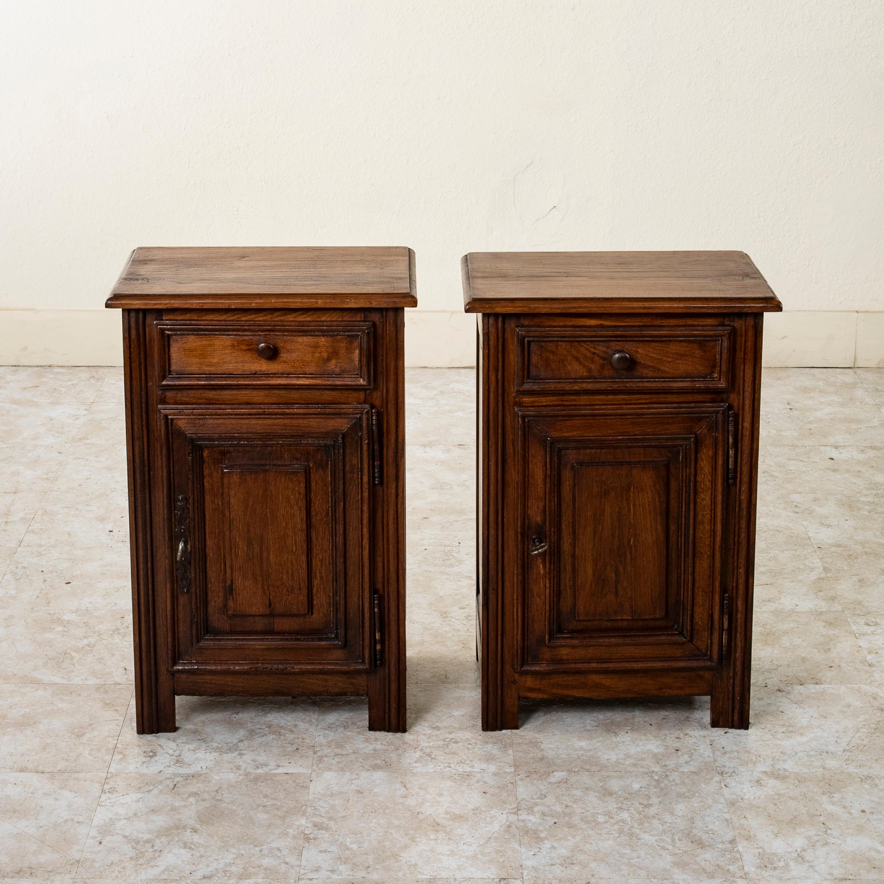 Found in the region of Normandy, France, this pair of early twentieth century rustic oak nightstands or bedside cabinets features solid hand pegged paneled sides in the Louis XIV style. Each cabinet is fitted with a single drawer above and a lower