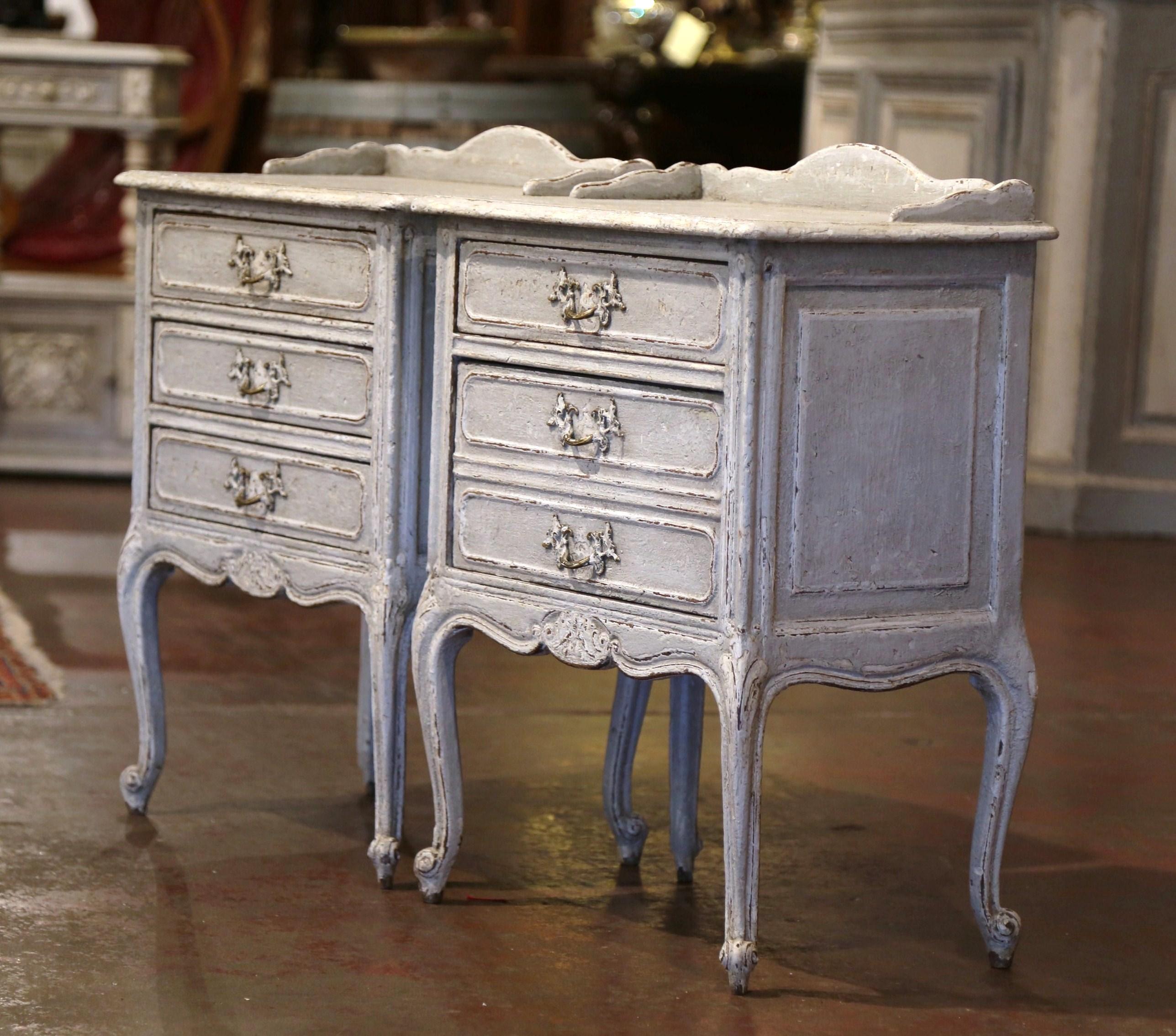 These elegant antique nightstands were created in France, circa 1900. Each Louis XV bedside table stands on cabriole legs decorated with acanthus leaves at the shoulder over a scalloped apron with a carved shell in the center. Both cabinets have