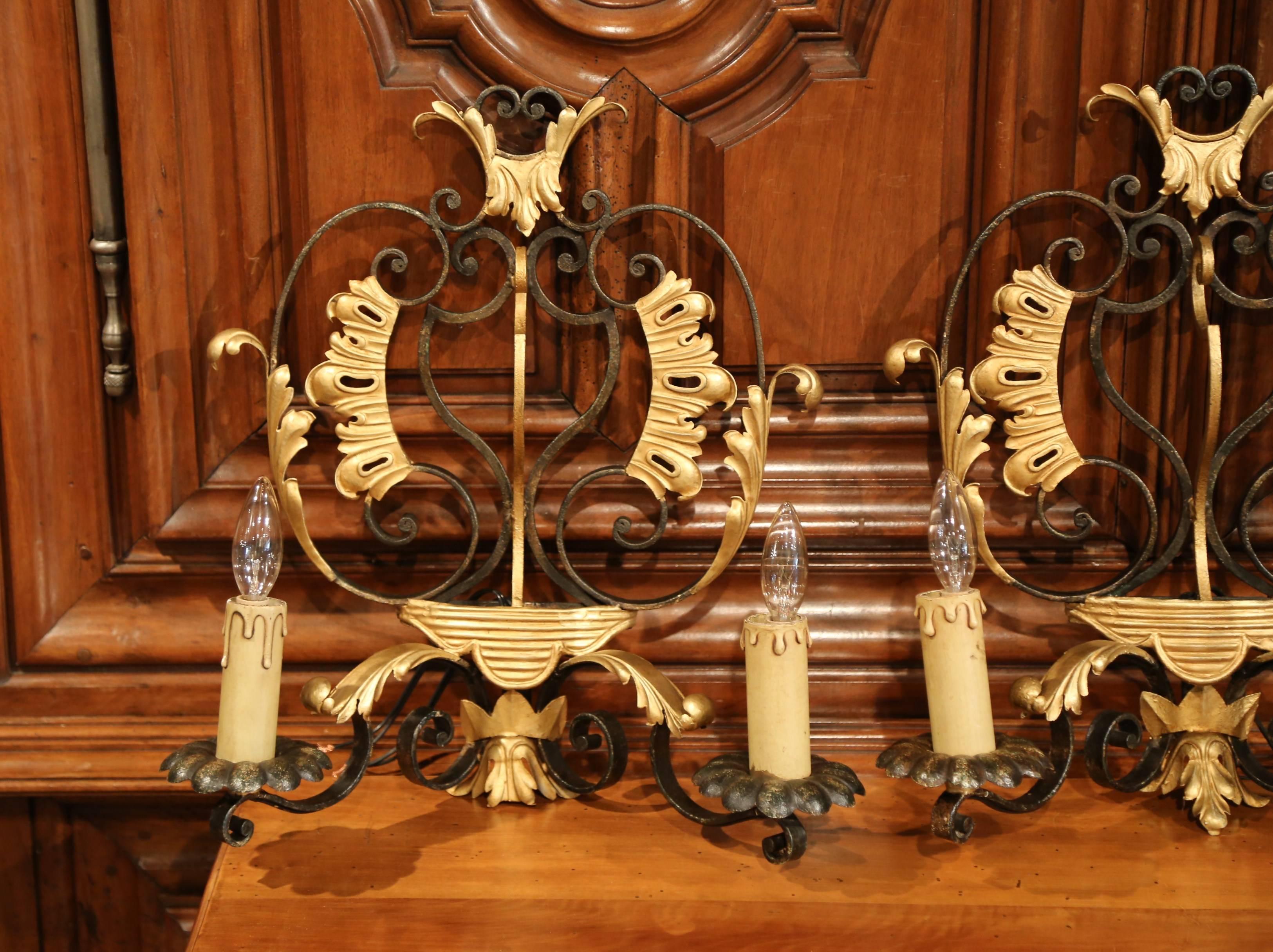 These matching antique wall sconces were crafted in France, circa 1920. Each sconce features two arms with newly wired lights over the original wood candle sleeves with drip; the back has painted leaves and decorative scrolled work. Both wall lights