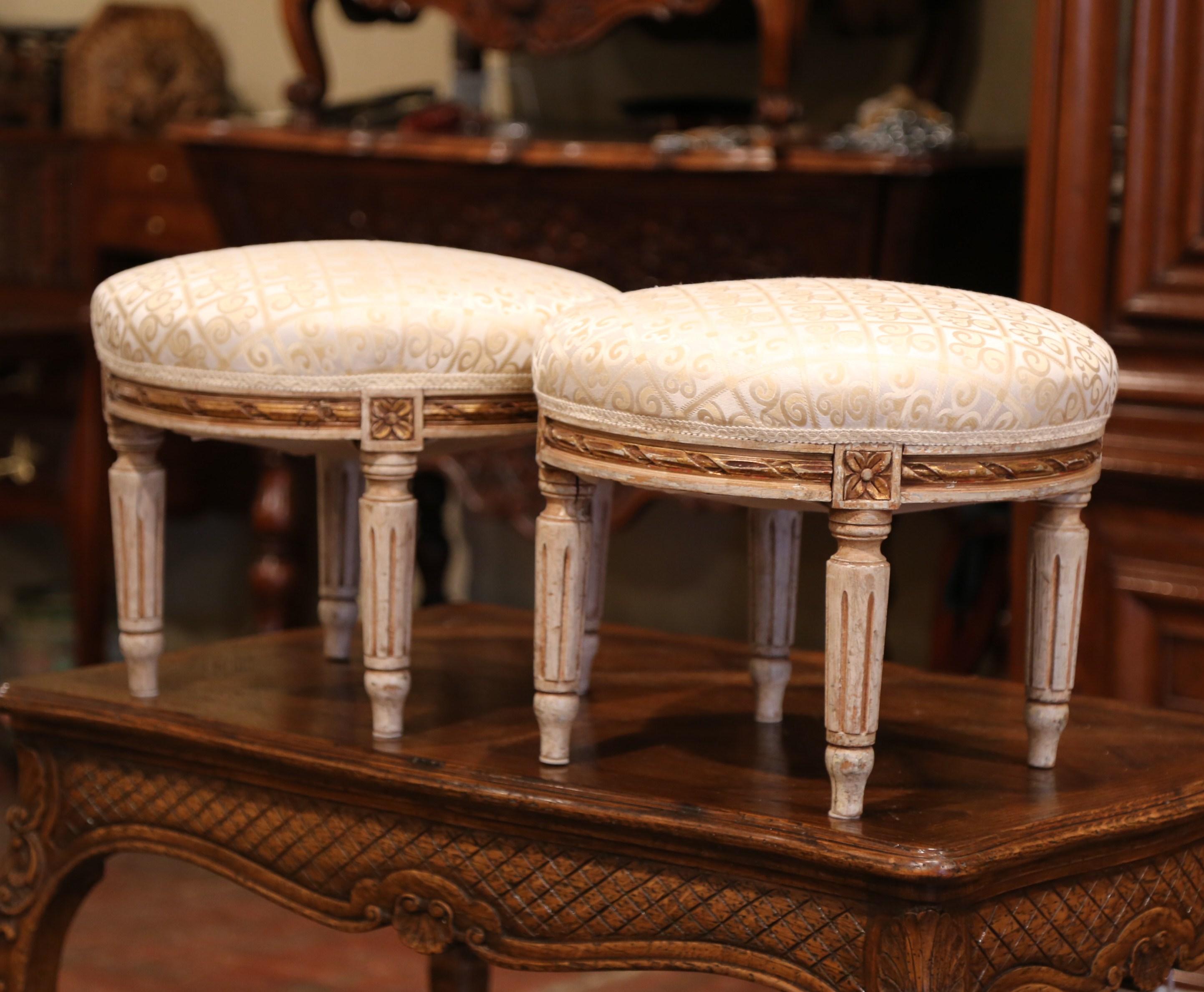 Elevate your feet while sitting in your favourite armchair with this elegant pair of antique footstools. Crafted in France, circa 1920, each round stool on four tapered legs, features a carved apron decorated with floral medallions, and have their