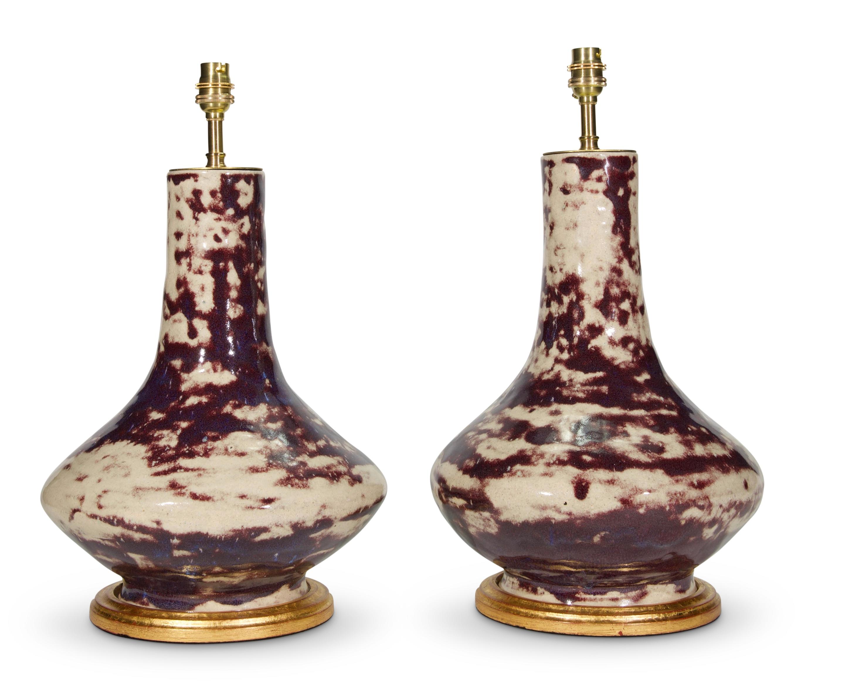 A fine pair of early 20th century French ceramic vases, with a wonderful mottled sang de boeuf flambé glaze, now mounted as lamps with hand gilded turned bases.

Height of vase: 14 1/4 in (36 cm) including gilded bases, excluding electrical