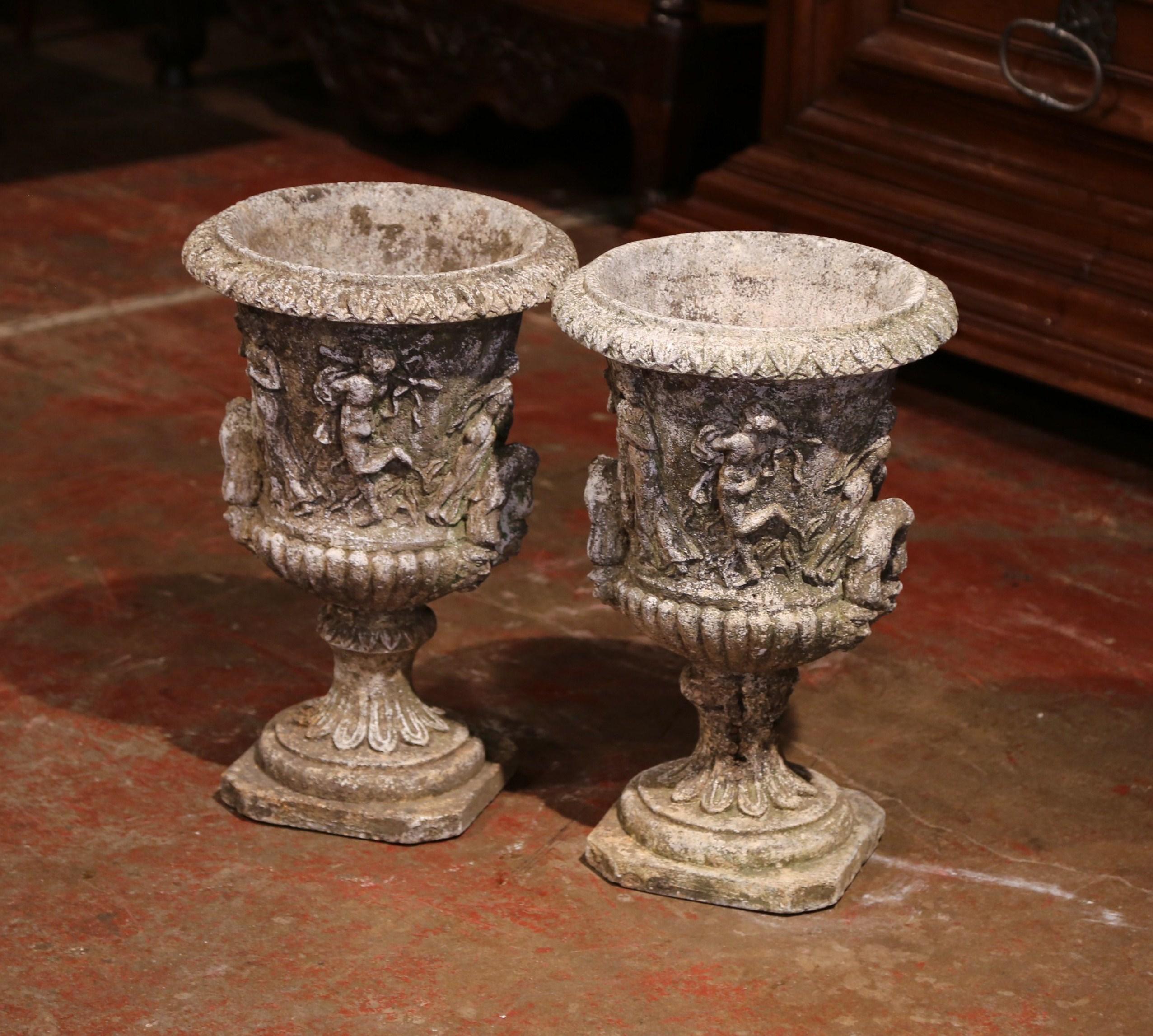 Decorate your porch or other outdoor sitting area with this pair of antique Medicis vases. Found in southern France and crafted circa 1920, the outdoor stone planters have side handles and feature delicate, allegoric scene carvings. The highly