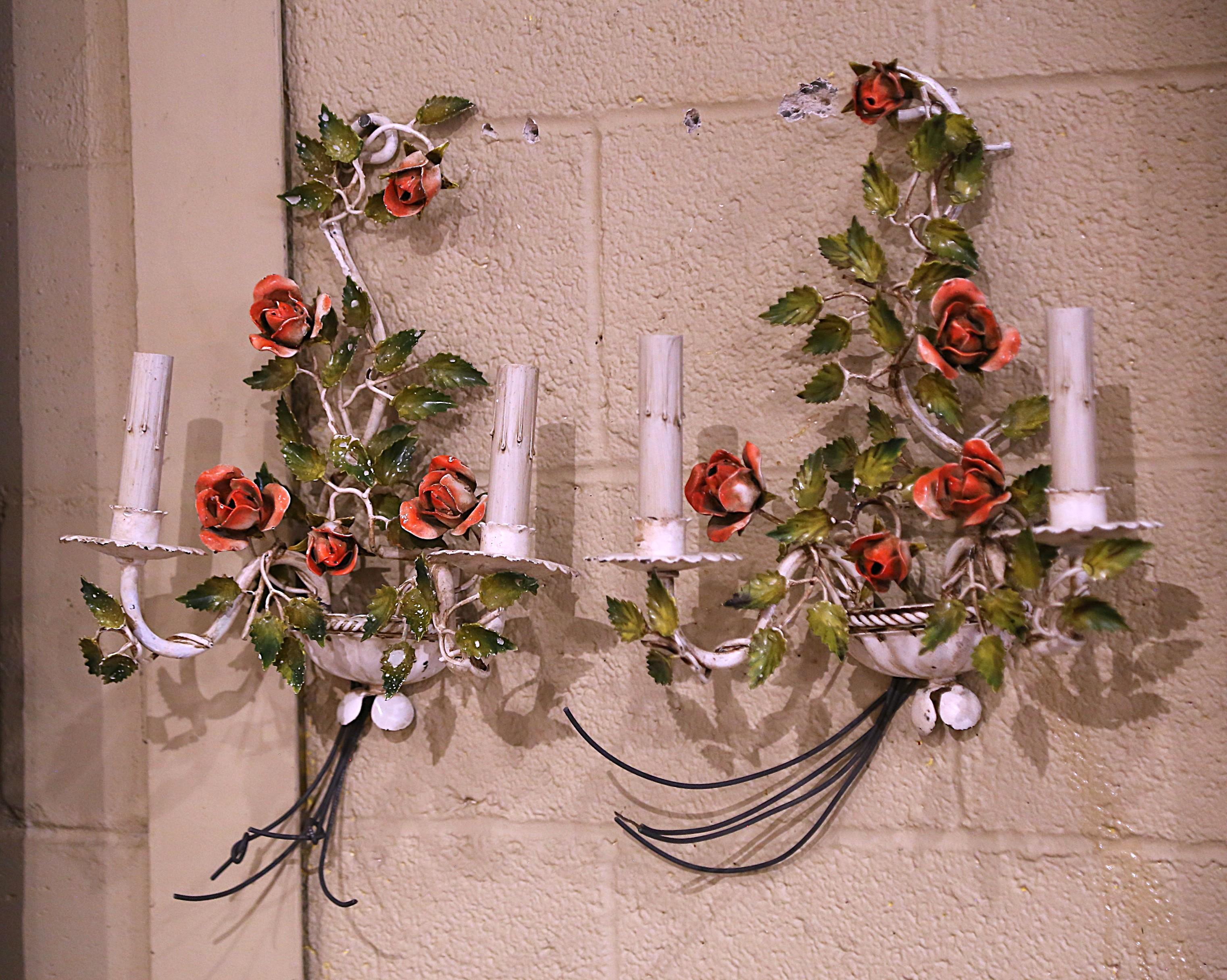 Decorate a bedroom or bathroom with this elegant and feminine pair of antique light fixtures. Crafted in France circa 1920, the colorful sconces are decorated with red rose flowers embellished with green leaves throughout. The sconces have two
