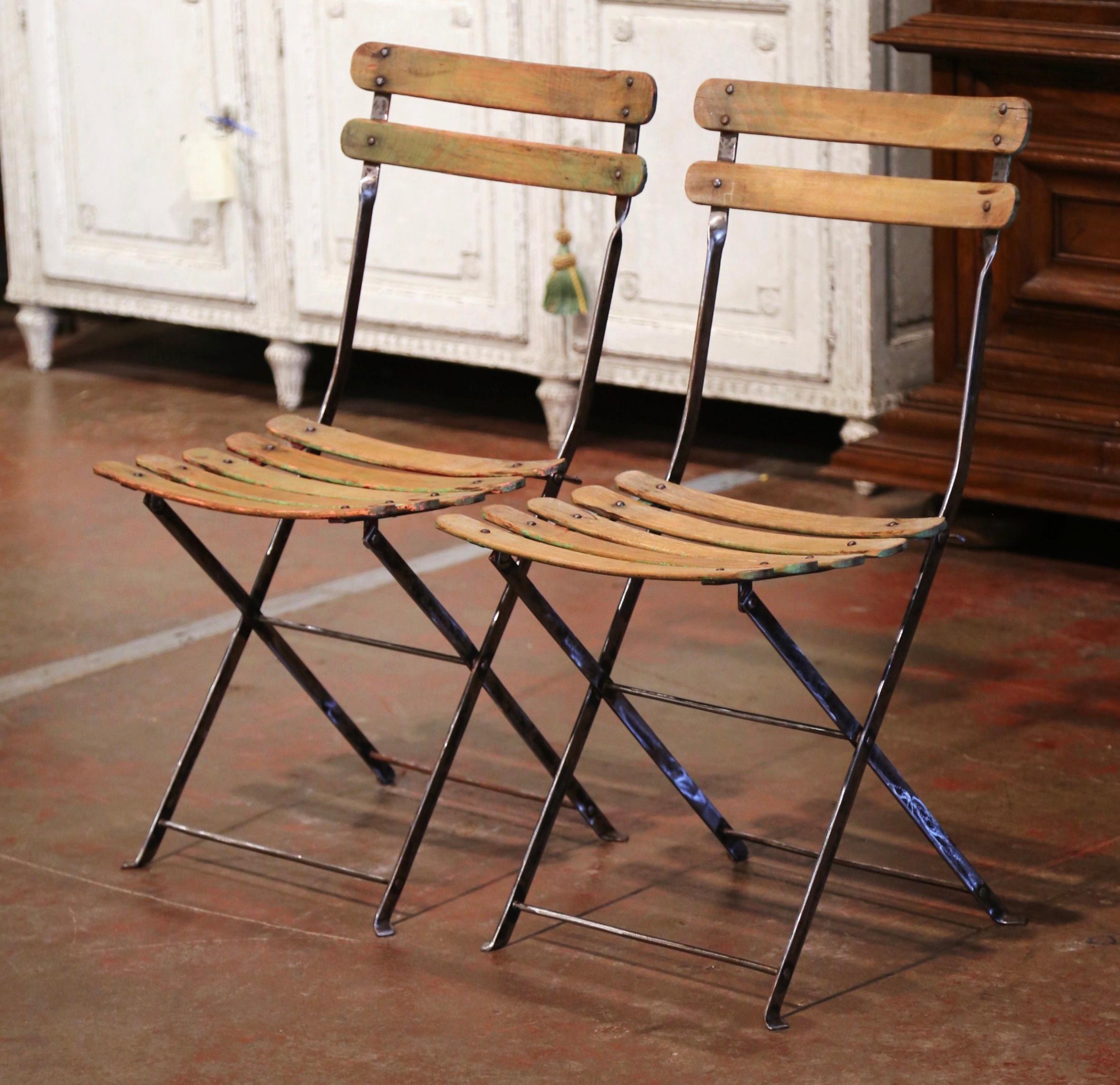 These antique chairs were crafted in Normandy, France, circa 1920. Made of iron and pine, each chair dressed with two-ladder back and five-slat seat, features a folding mechanism for ultimate compact storage (less than 2