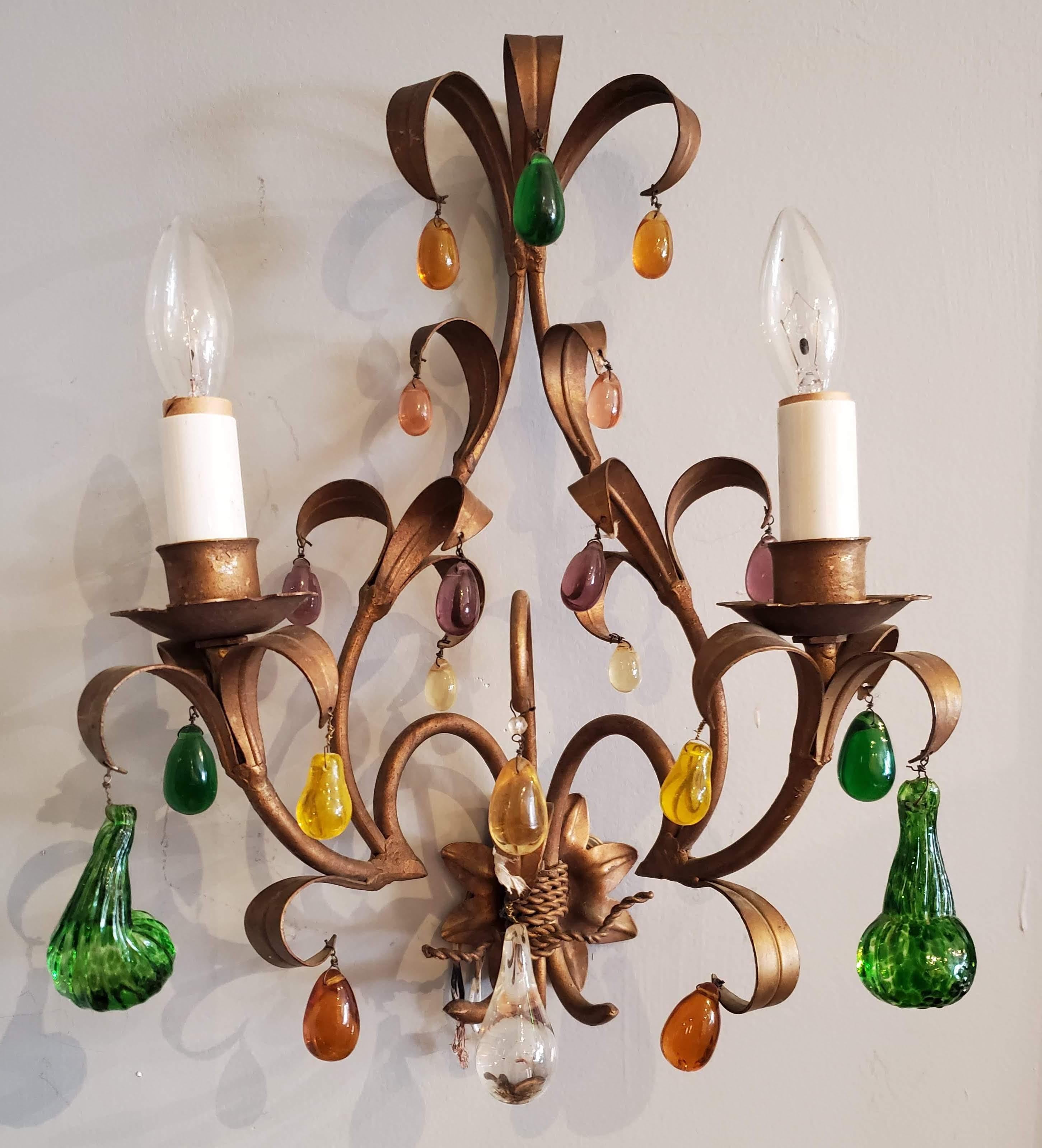 Add a little whimsy to the room with this pair of early 20th century French provincial wall sconces. Each sconce has two candle lights with delicate leaf motifs and whimsical multicolored glass pendants in the form of fruit. Bronze finish on the