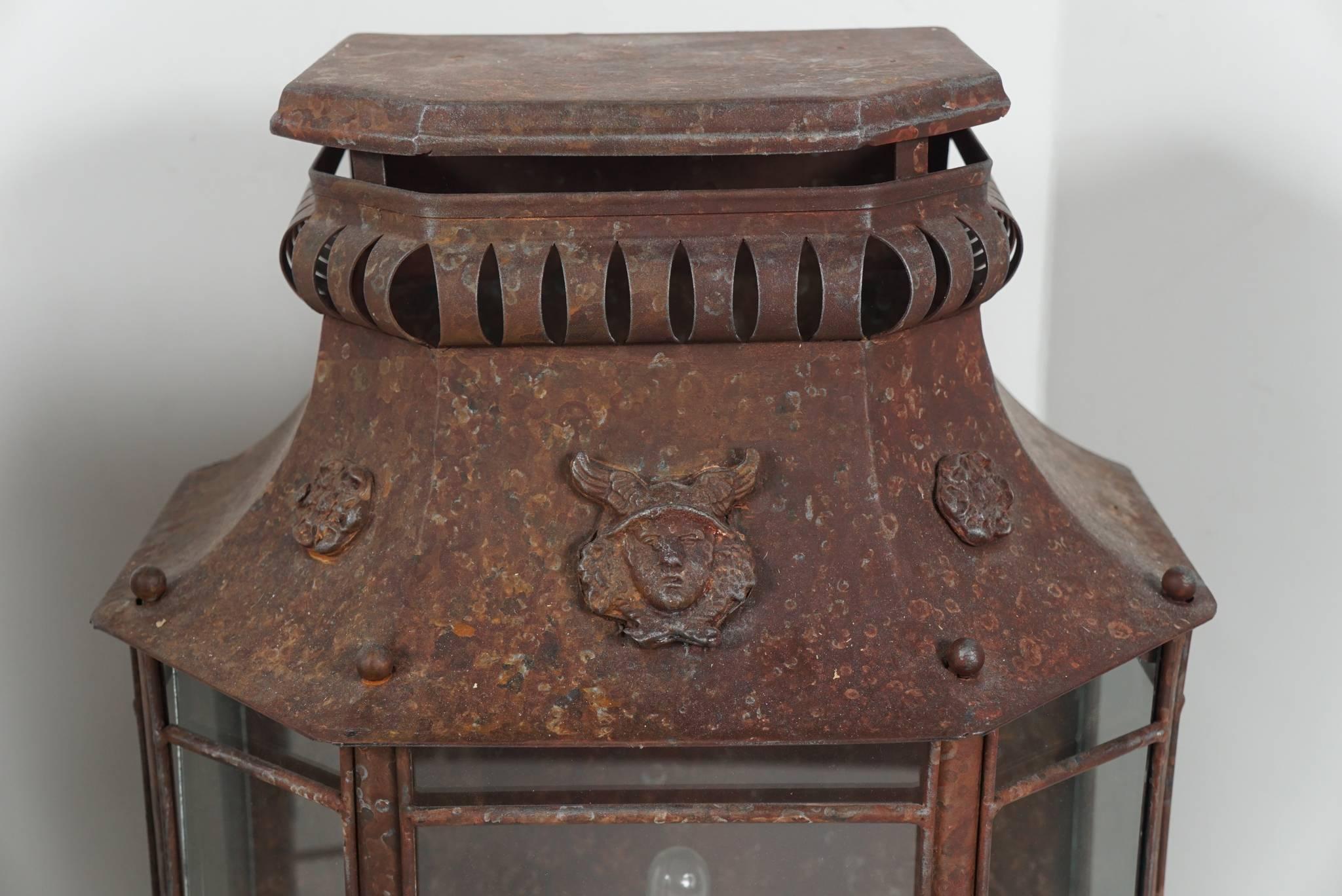 This pair of large-scale lanterns designed as wall-mounted lighting was made in France, circa 1920. Designed in an antique fashion the work is handmade and they have acquired a magnificent old patina. The form is further enhanced with cast and