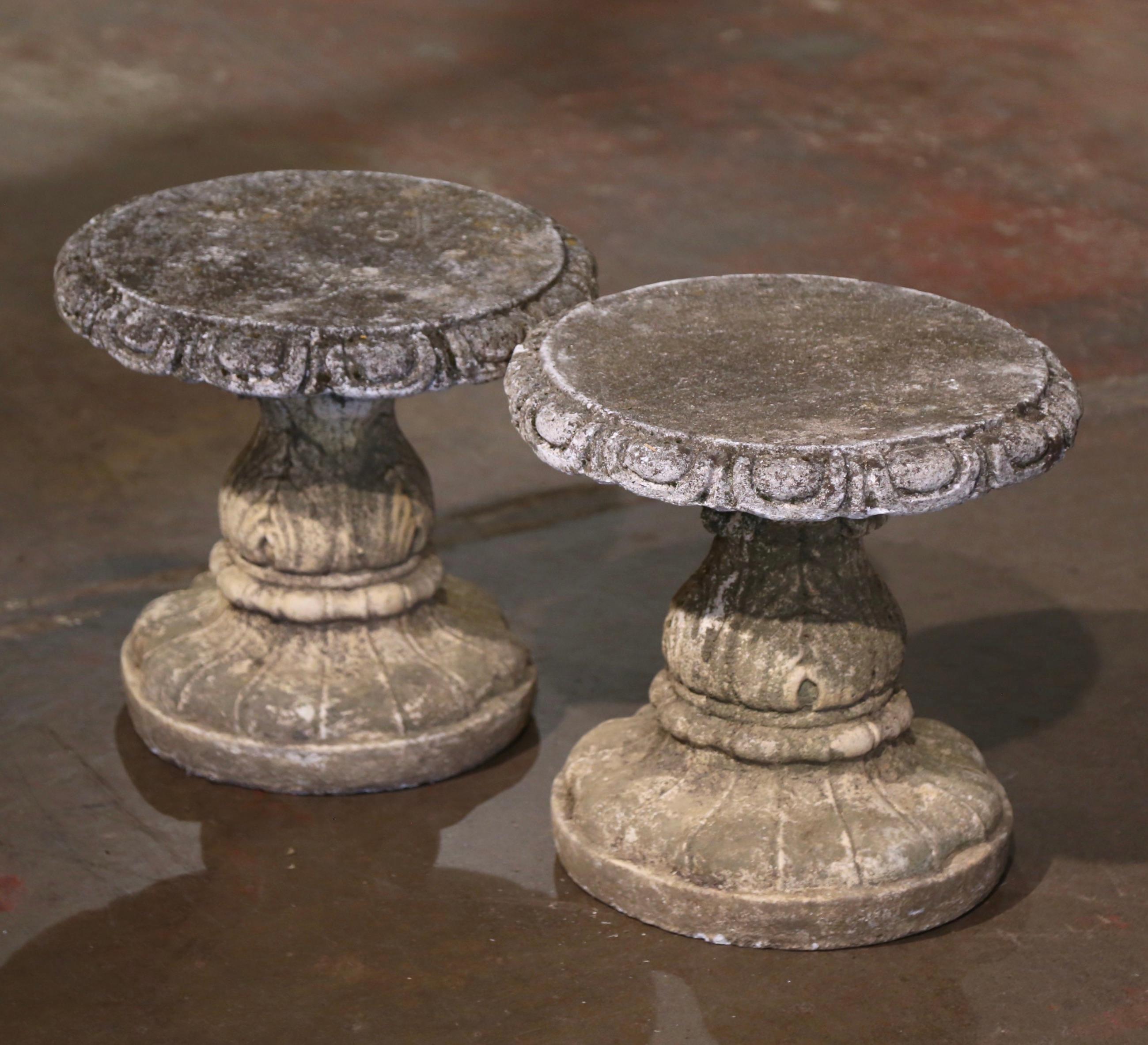 Decorate a patio or a garden with this elegant pair of antique stools. Crafted in Normandy, France circa 1920 and built of concrete, each stool stand on a carved pedestal base with acanthus leaf motifs over a circular seat with molded trim edges.