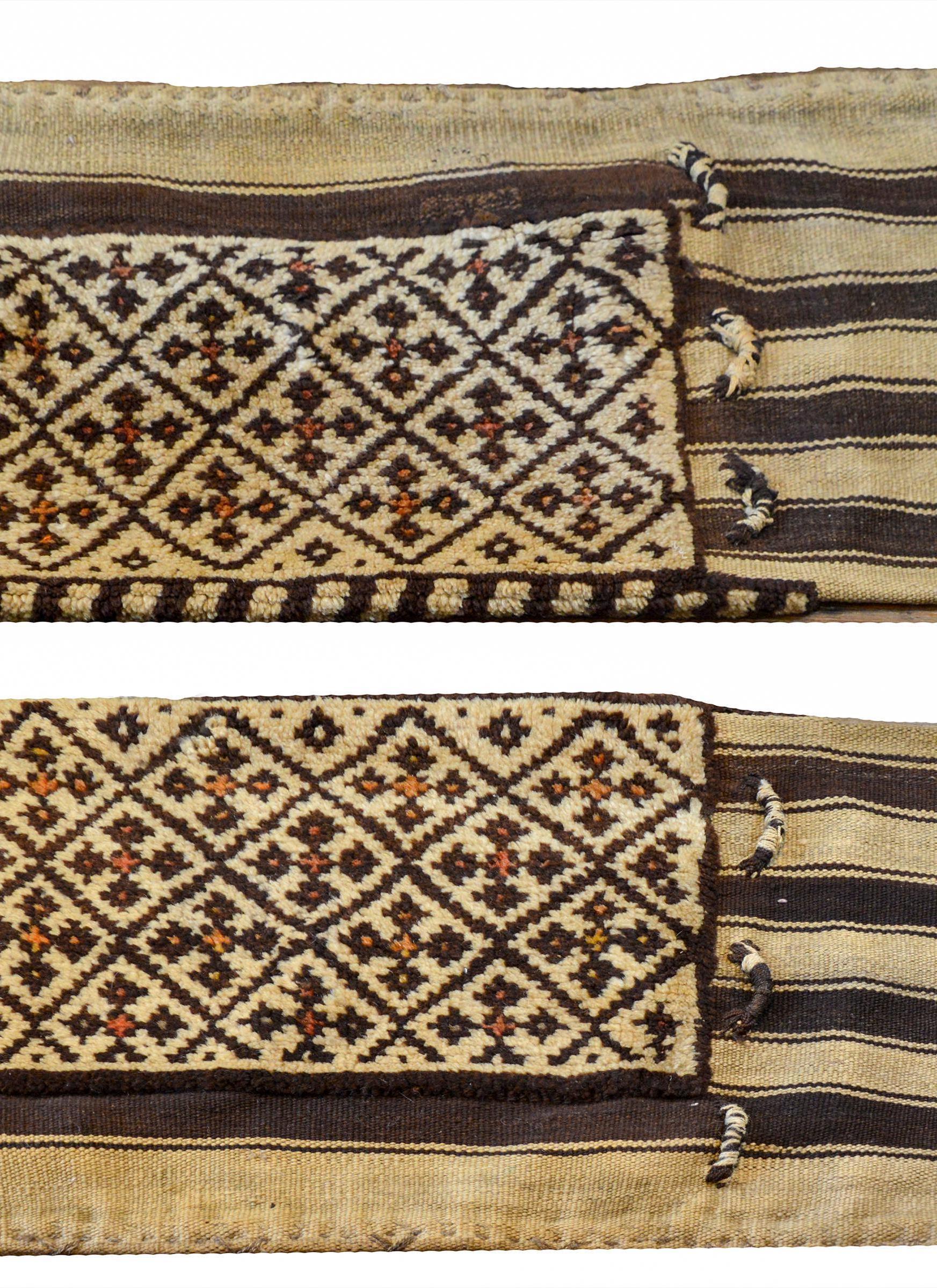 A fantastic pair of early 20th century Persian Gabbeh grain bags, each with a cross pattern woven in brown and white wool with orange details. The backs are flat-weave with brown and white stripes.