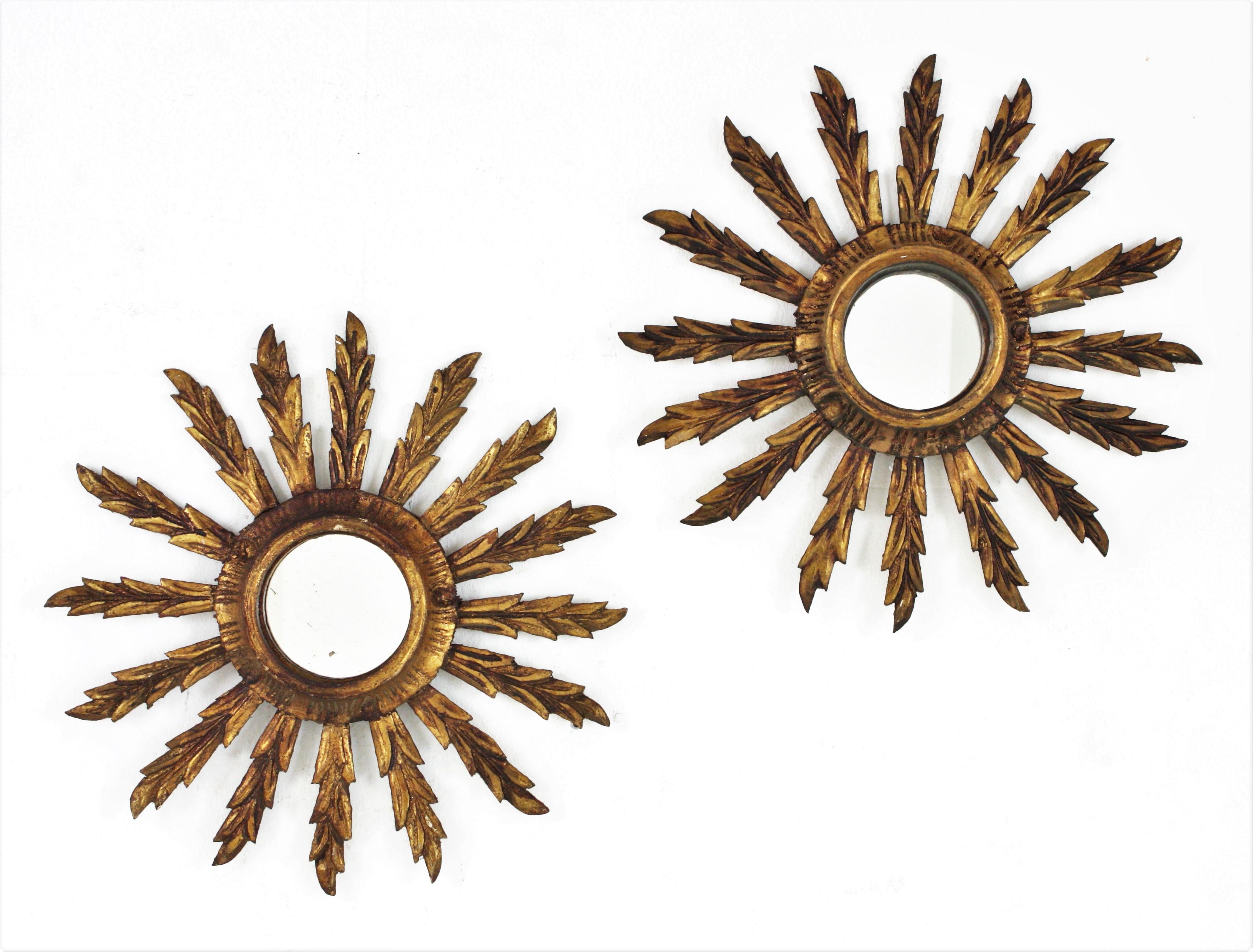 Spanish Giltwood sunburst mirrors in Small Scale, Spain, 1930s-1940.
Beautiful pair of sunburst mirrors in this unusual mini size and Baroque style. Carved wood covered with gesso and gold leaf finish.
Terrific age patina. 
Slightly difference in