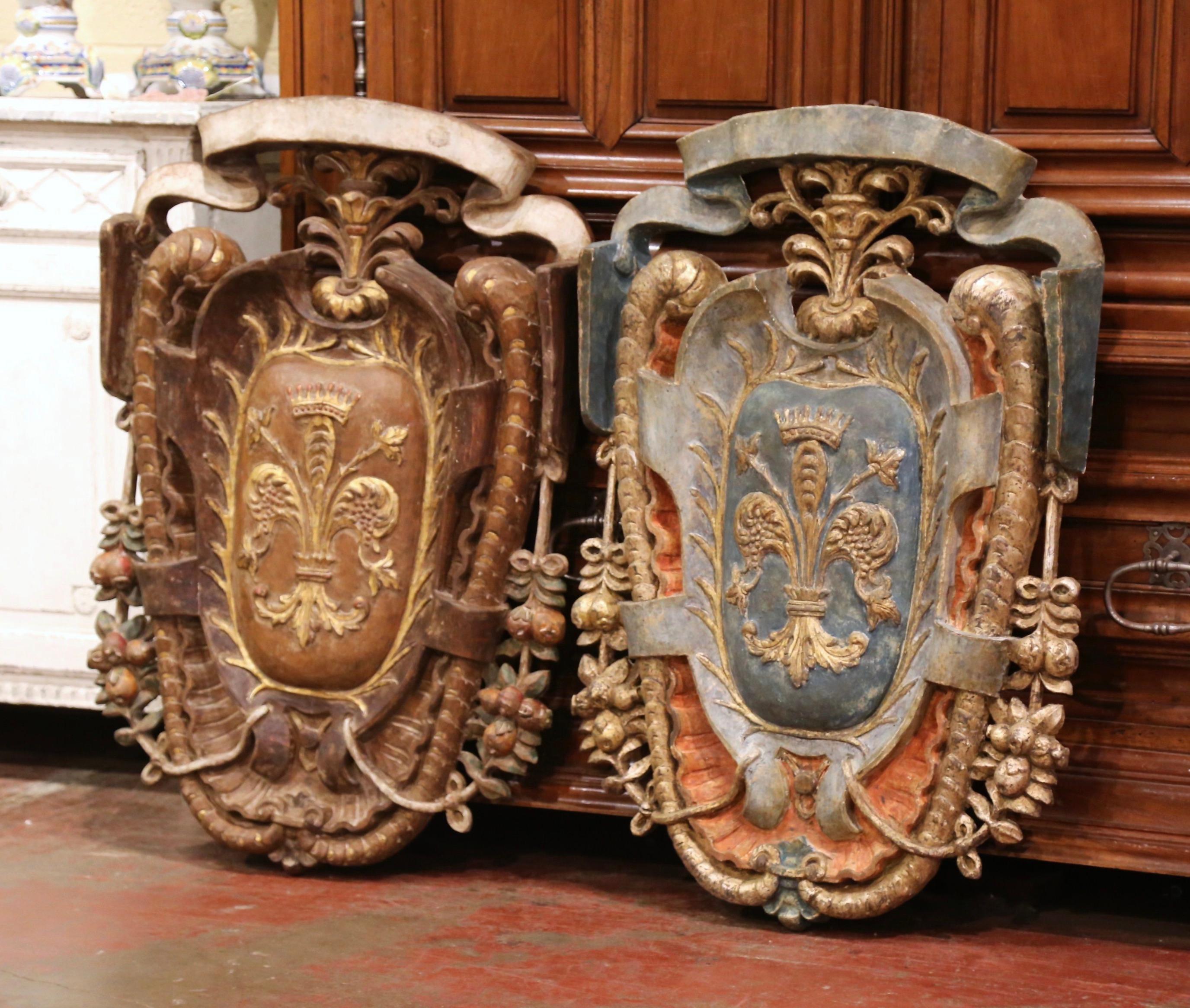 Decorate a study or library with this important pair of antique shields. Hand crafted in Italy, circa 1920, each traditional crest is heavily carved with fruit and foliage motifs over a pierced floral decor at the pediment. The large wall decors