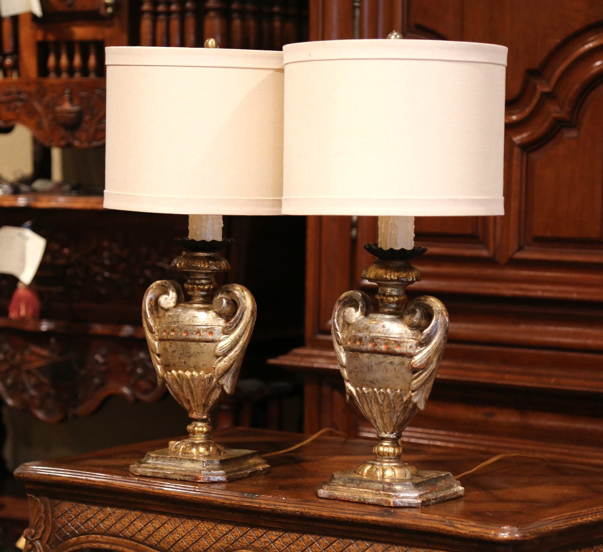 Place these elegant antique lamps on a pair of bedside tables or on top of a console in an entry! Crafted in Italy circa 1920, each hand carved lamp sits on a square base and features a Medicis vase shaped embellished with carved leaf handle motifs.