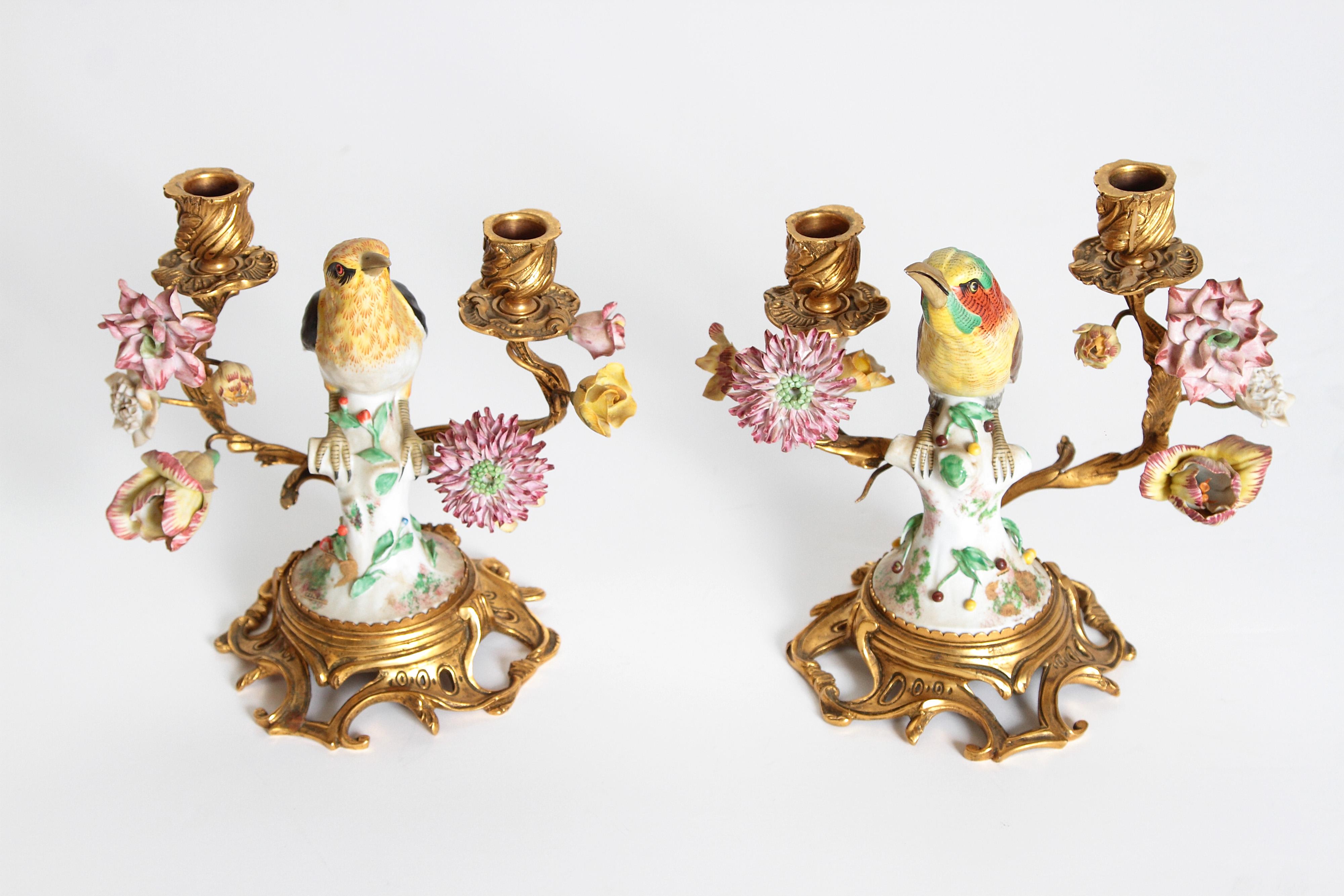 A lovely pair early 20th century Louis XV style two-light candelabra each with a porcelain bird combined with fanciful gilt-bronze mounts set on a rococo gilt-bronze base. The birds are flanked by hand painted porcelain flowers mounted on