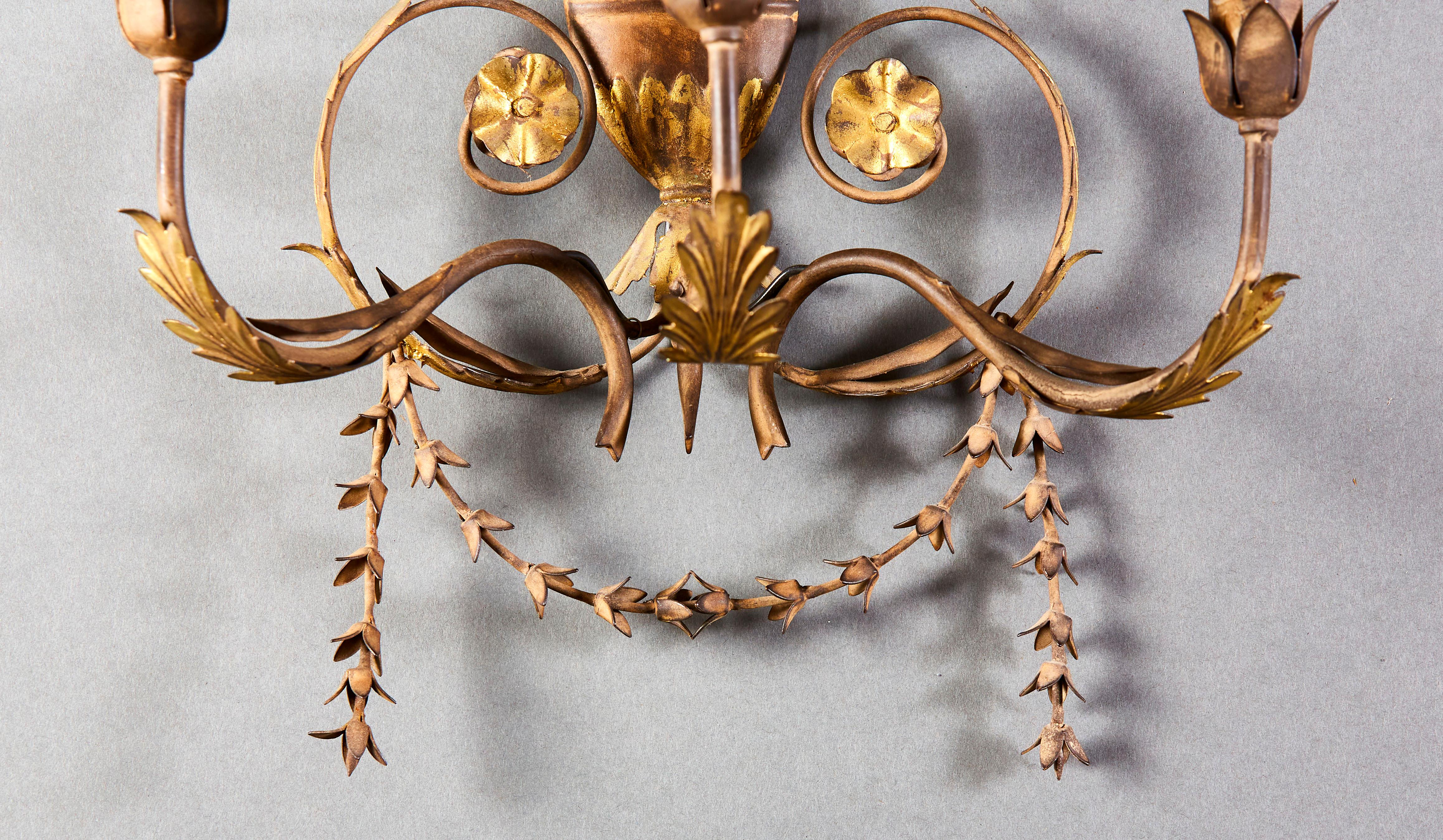 Pareja de apliques de tole pintados de principios del siglo XX, con guirnaldas de hojas, decoración neoclásica, hojas de maíz y páteras doradas, cada uno con tres brazos de vela.

Altura   74.00cm
Anchura    35.00cm
Profundidad    23.00cm

Tenga en