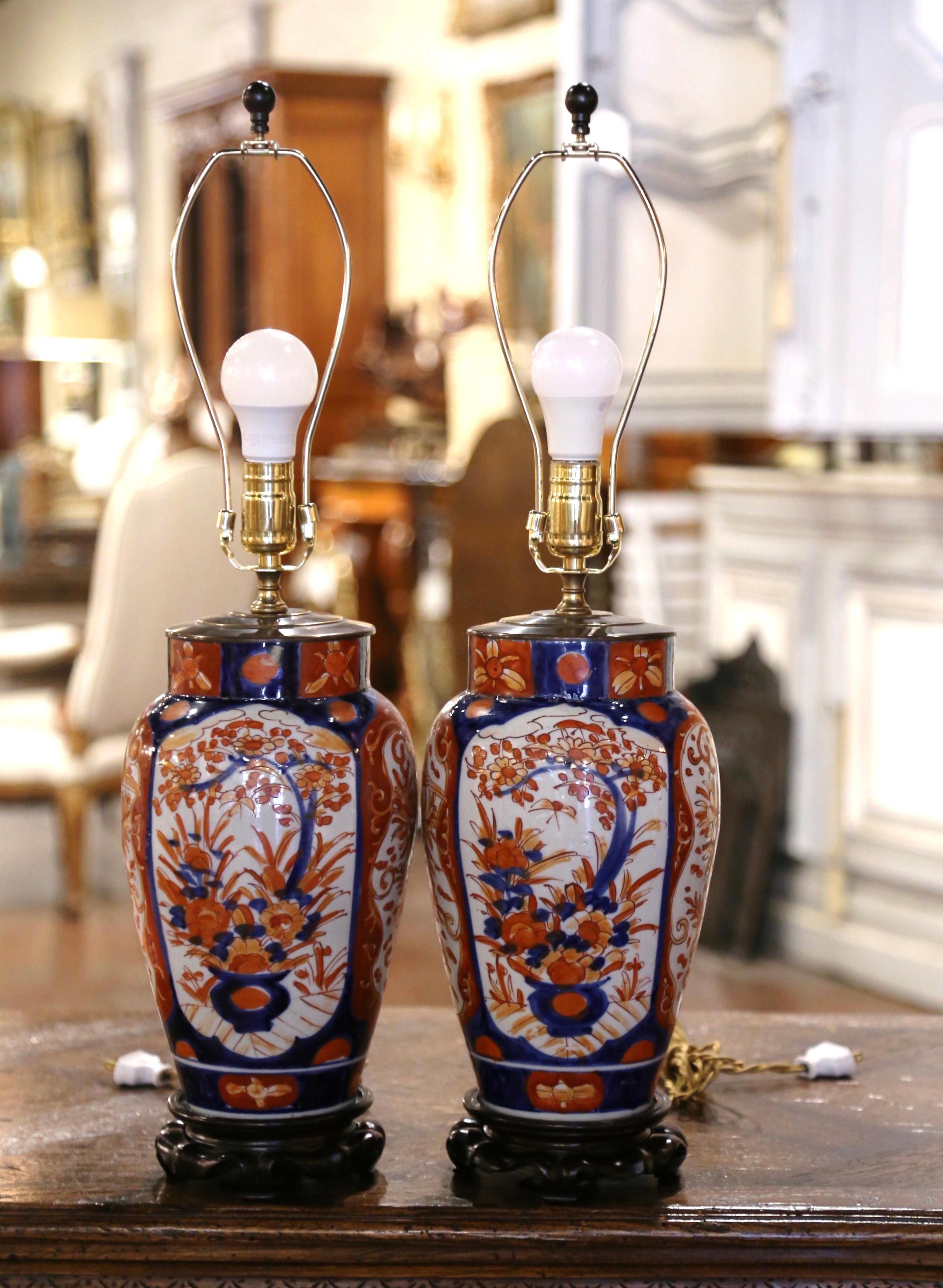 Add the perfect amount of color into your home with this pair of antique lamps. Created in Japan circa 1920, and round in shape each porcelain lamp rests on a wood base, and is decorated at the neck with a brass mount. The ceramic vases are both