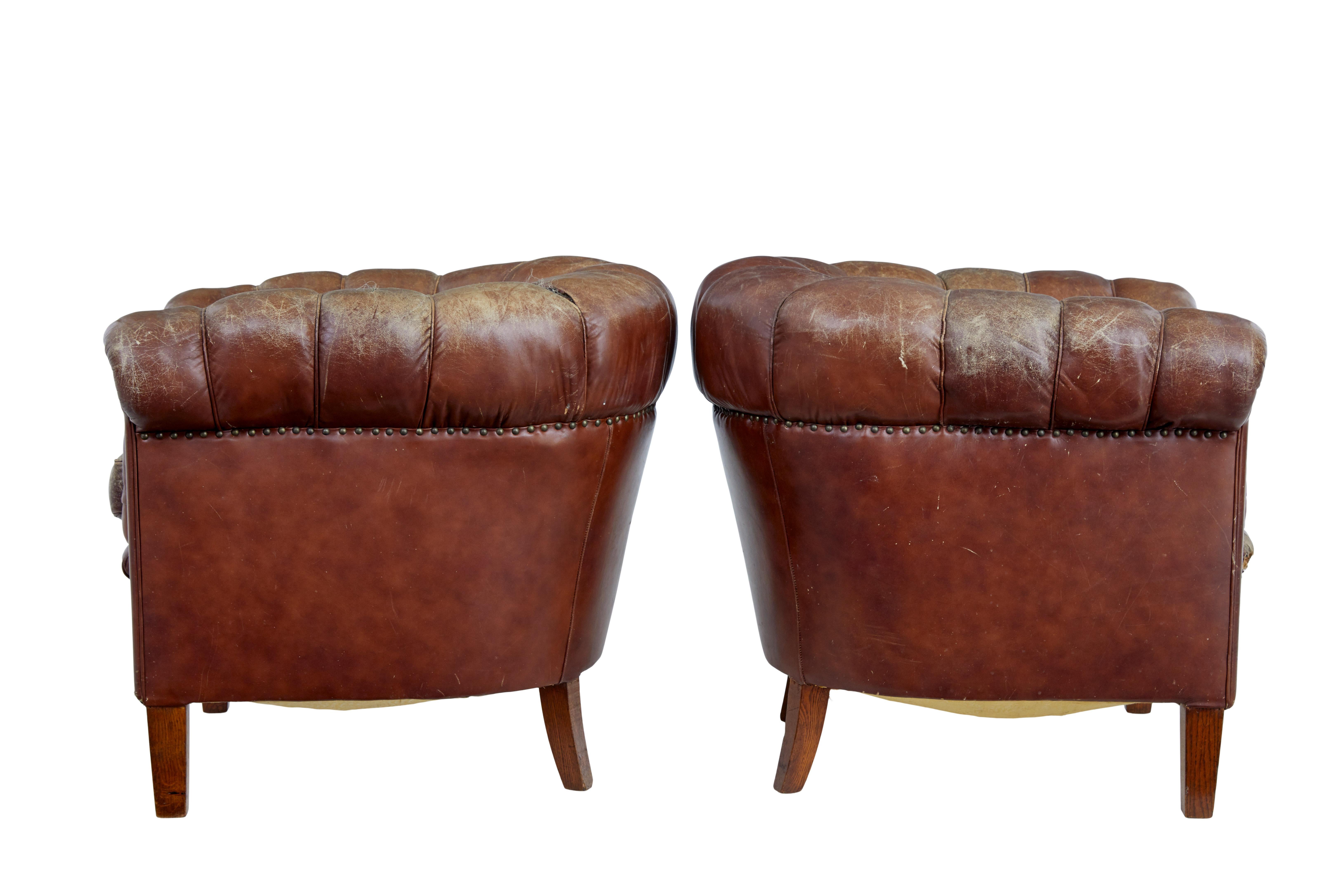 Pair of 20th century leather lounge armchairs circa 1920.

Very comfortable pair of 1920's leather button back armchairs. Over stuffed roll top arms, with seperate seat cushion. Each standing on 4 tapering oak legs.

Obvious fading, splits and