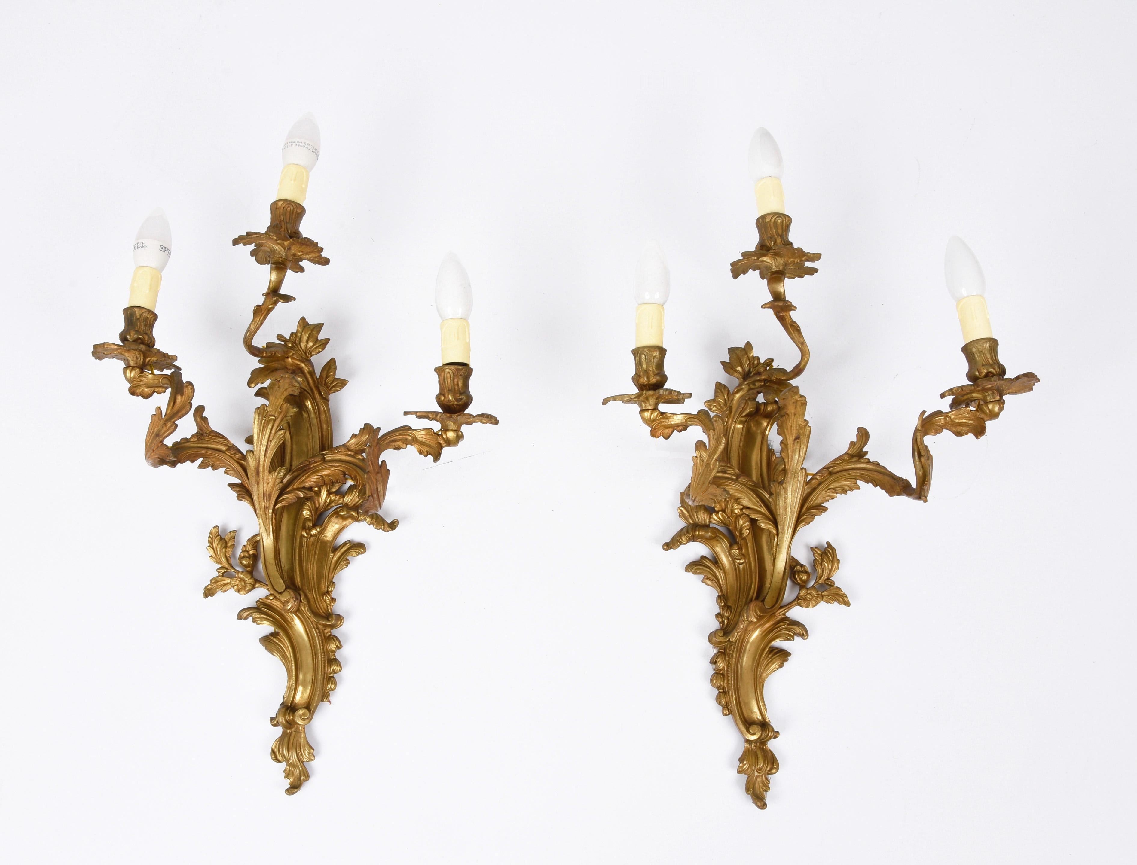 Sumptuous pair of early gilded bronze and brass scones. This fantastic set was made at the beginning of the 20th century in the style of Louis XV in France.

This luxurious pair is decorated with acanthus leaves and a floral theme. They were