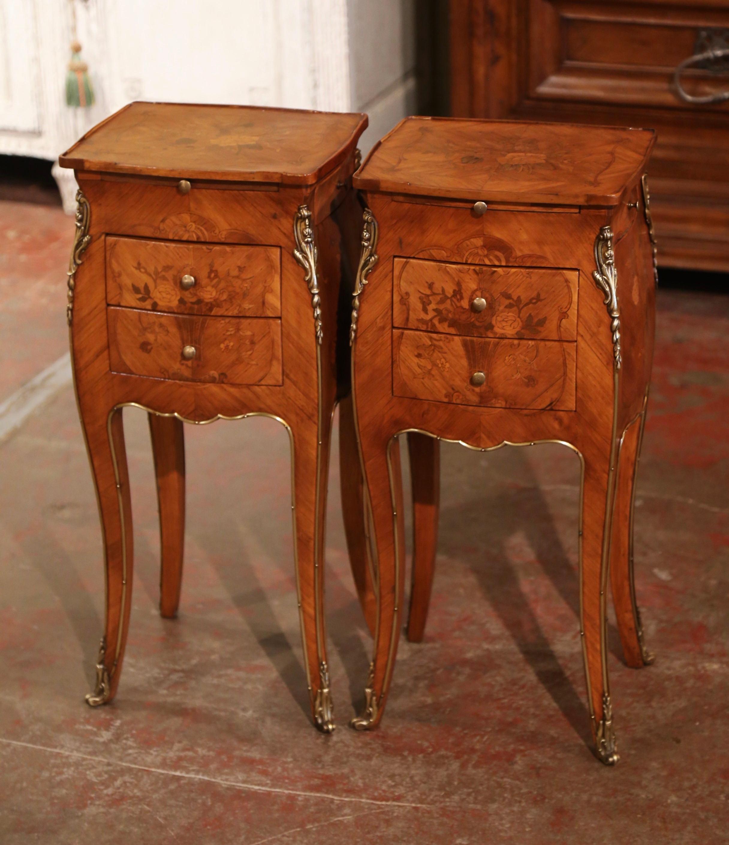 These elegant bedside tables were created in France, circa 1920. Bombe in shape on all three sides, each fruitwood cabinets stands on cabriole legs decorated with brass embellishments and ending with bronze sabot feet; the front features a scalloped