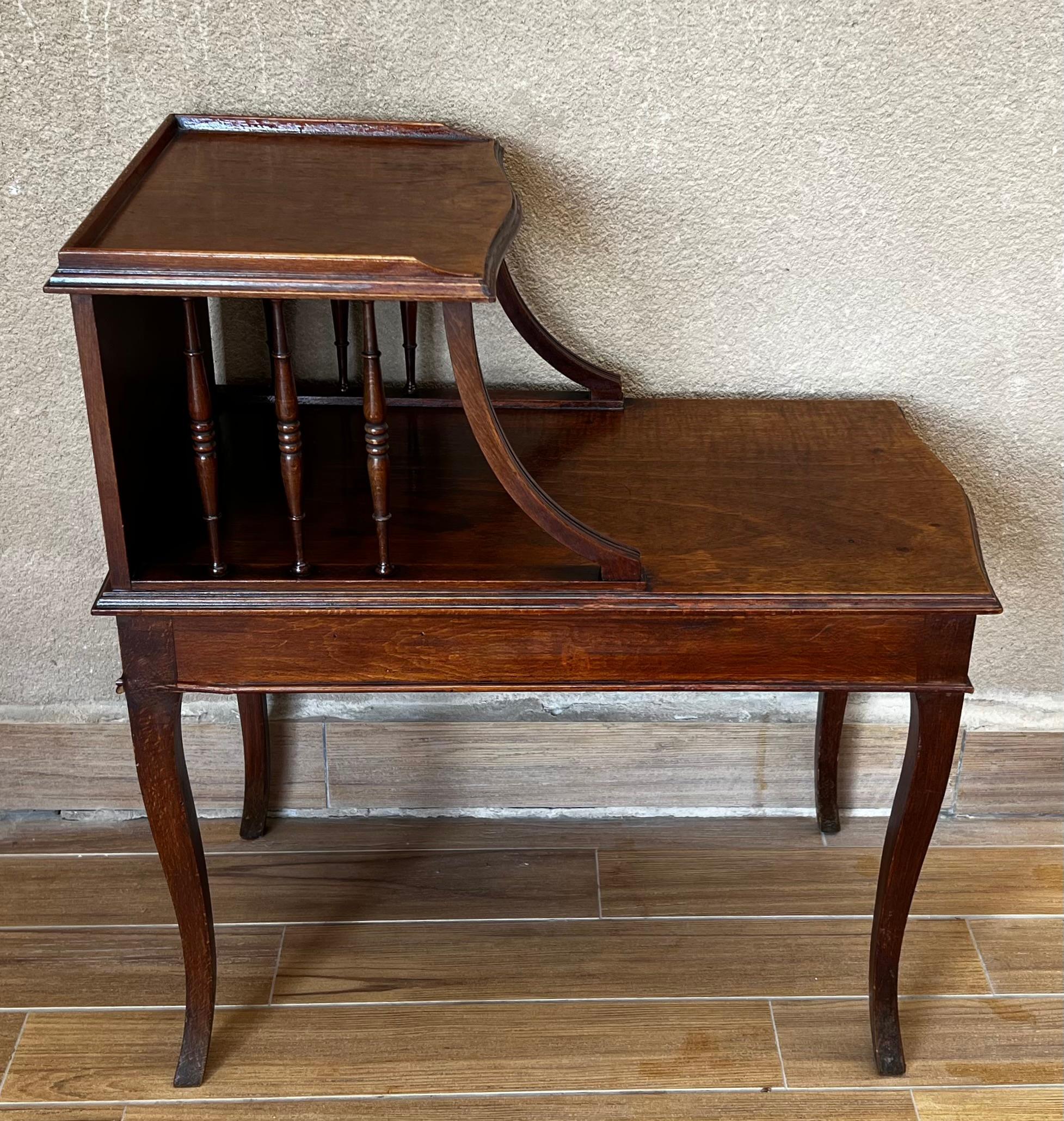 These elegant antique tables were created in Provence, France, circa 1920. Each walnut cabinet stands on cabriole legs over a bombe and scalloped apron. The table features a two-tier plateau with pierced sides and back in between, and the top