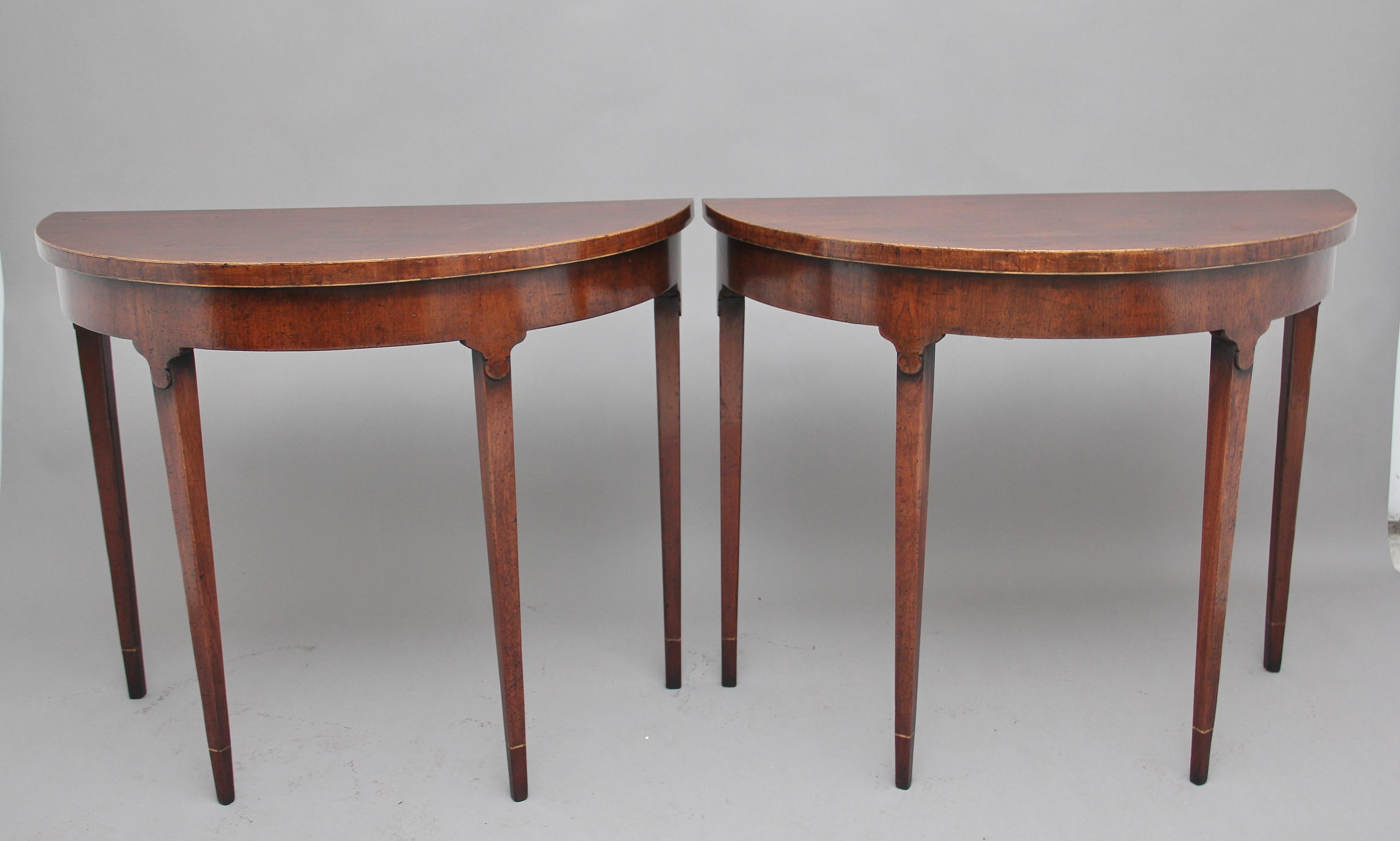 Pair of early 20th century Georgian style mahogany demilune console tables, the solid mahogany tops with boxwood white line, nice shaped detail at the bottom of the apron, supported on four square tapering legs, circa 1920.