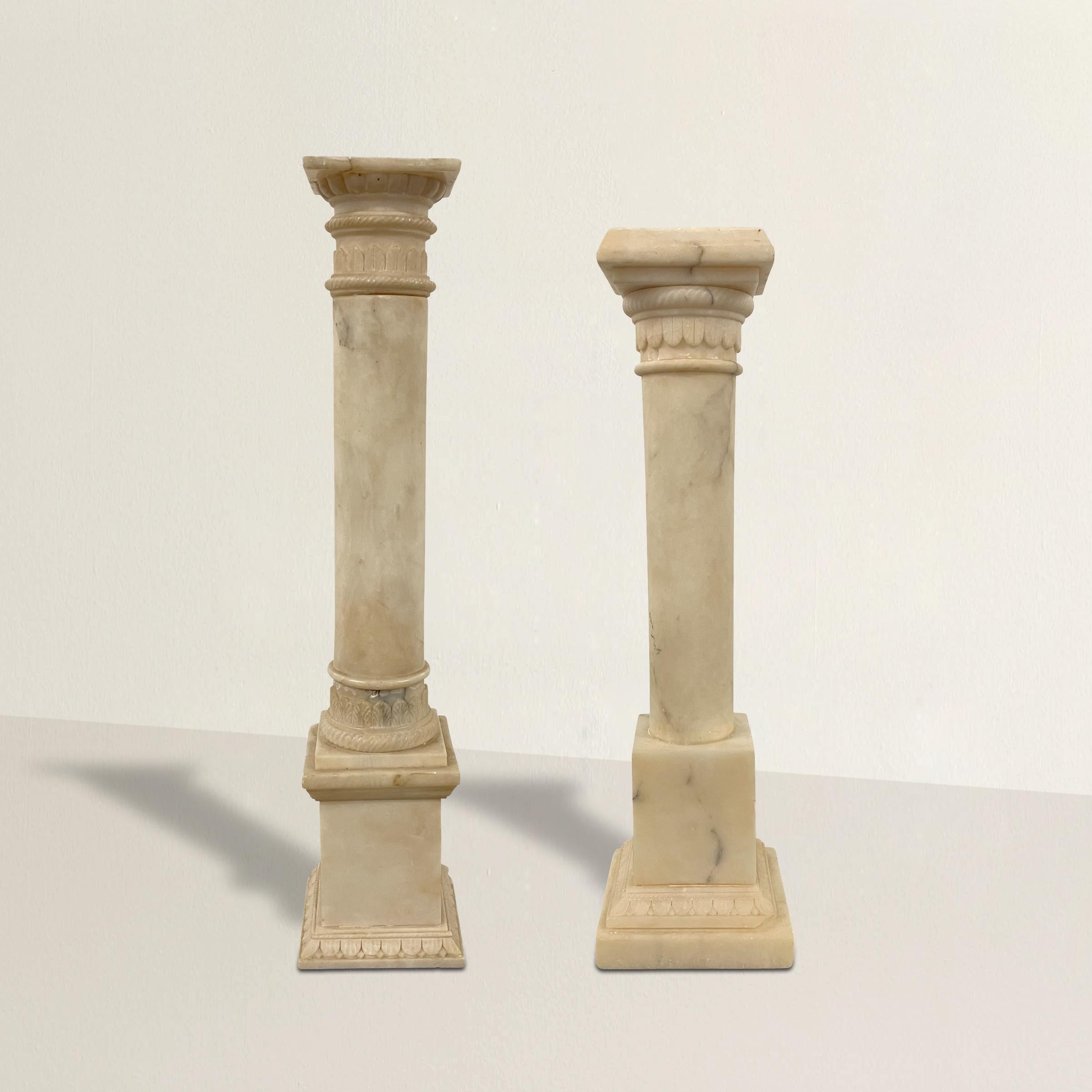 Pair of early 20th century Italian neoclassical-style alabaster columns, reminiscent of Grand Tour souvenirs, with carved acanthus leaf details, and each resting on square bases with more carved leaf details.

Measures: Shorter: 3.63 in. W x 3.63