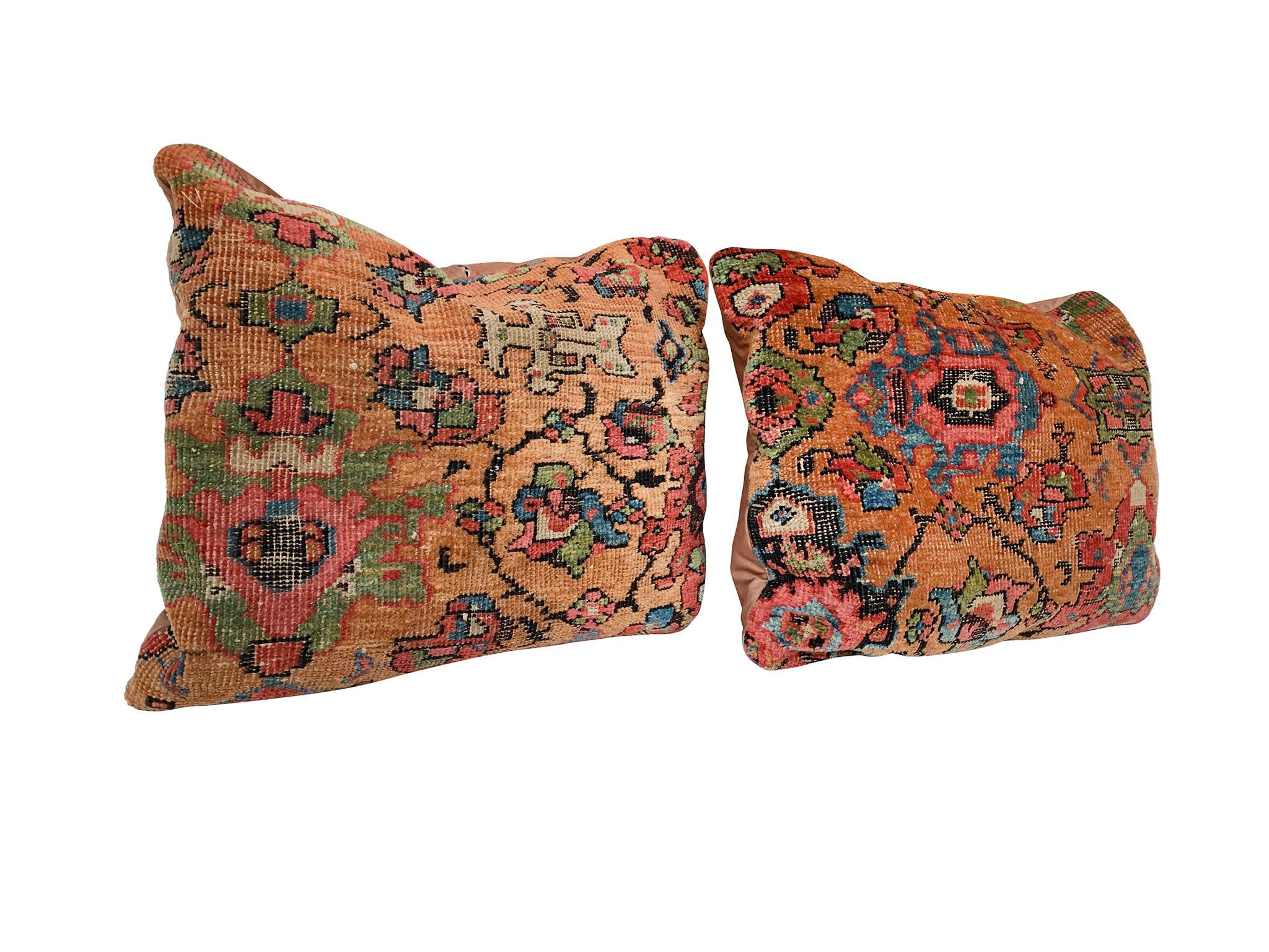 A pair of pillows consisting of fragments from a Persian rug that was itself hand-made in the Early 20th Century. The design is a rich pattern of floral and geometric motifs in a palette of copper-brown, red, blue, green, black, and yellow. The