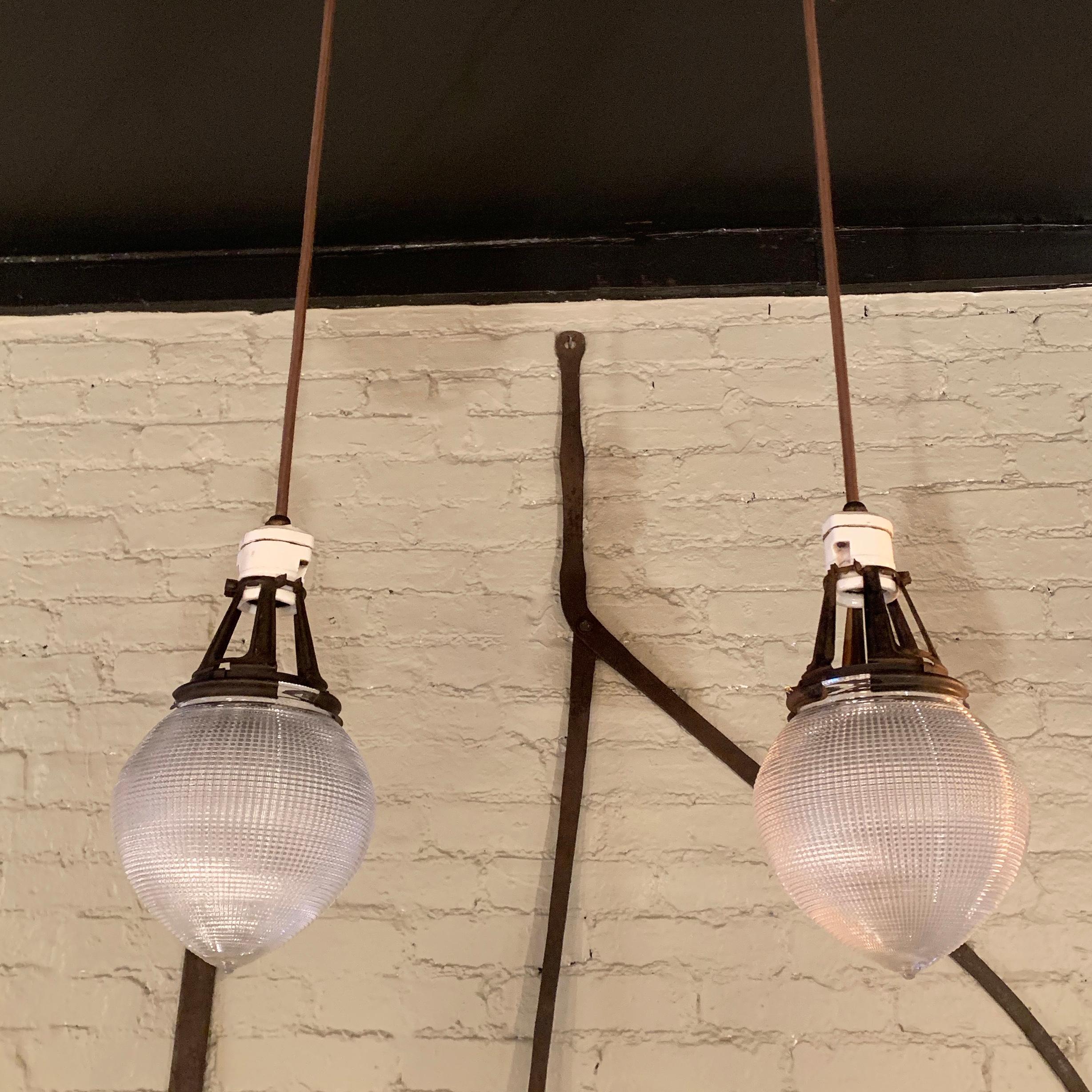 Pair of acorn shaped, prismatic, Holophane pendant lights feature elongated brass, X-ray fitters with porcelain paddle switch sockets are newly wired with 36 inches of brown cloth cord.
