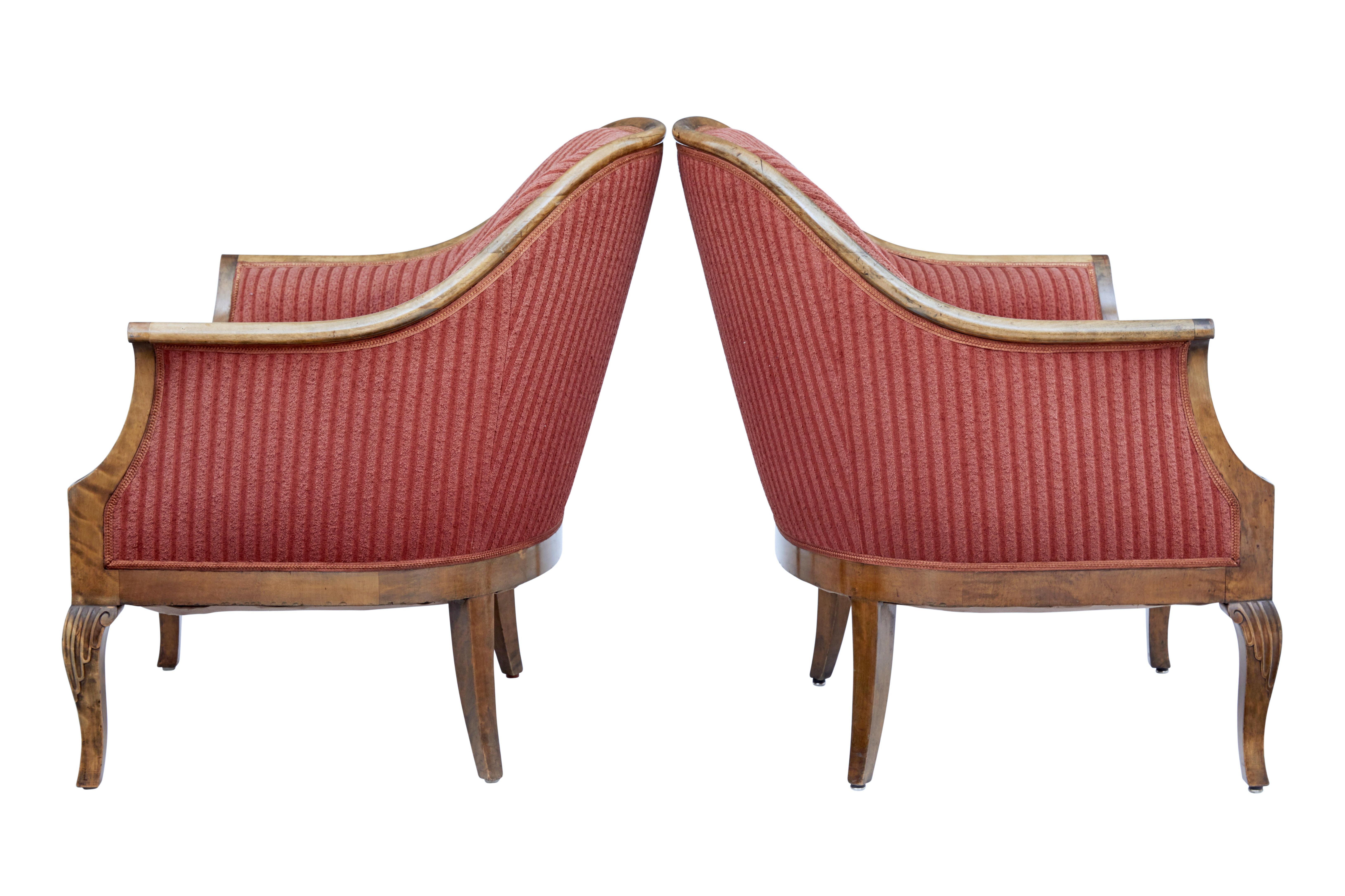 Pair of shaped back birch armchairs circa 1920.

Comfortable pair of lounge chairs which flow down from the back to the arm. Carved detail to the arm fronts and carved shell design to the knee of the front leg.

Tapered back legs.

Minor