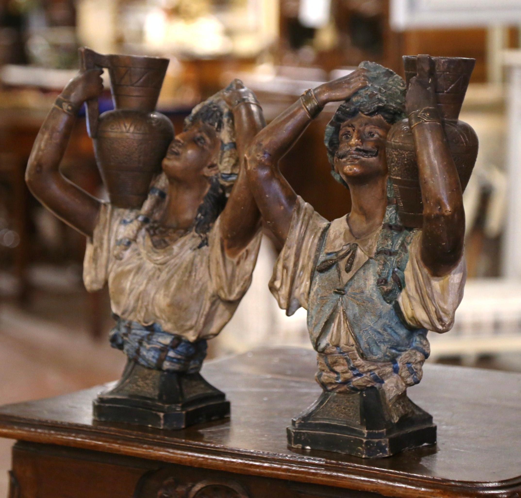 Diese antiken Terrakotta-Figuren wurden um 1920 in Spanien hergestellt. Jede Figur stellt eine fein gearbeitete Büste eines Mannes und einer Frau dar, die beide amphorenähnliche Gefäße auf den Schultern tragen. Die Figuren sind in traditioneller