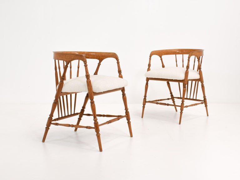 A pair of early 20th-century chairs with rounded spindle back and legs. The design was inspired by 19th-century smokers bow or captains chairs. 

These chairs combine elegance with comfort and their soft colors will blend into any interior style.