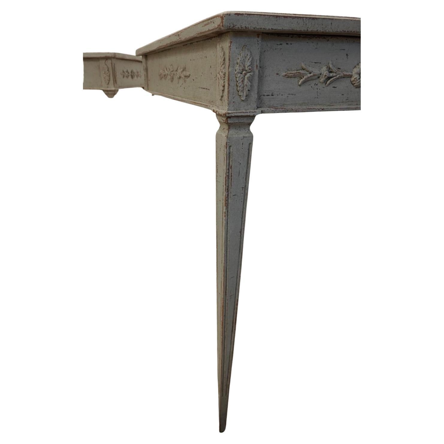 Pair of side tables in Gustavian style, crafted from pine and painted in light grey. 

The tabletops have a profiled edge, and the apron features decorative carvings, including floral rosettes and acanthus leaves in the corners. The tables rest on