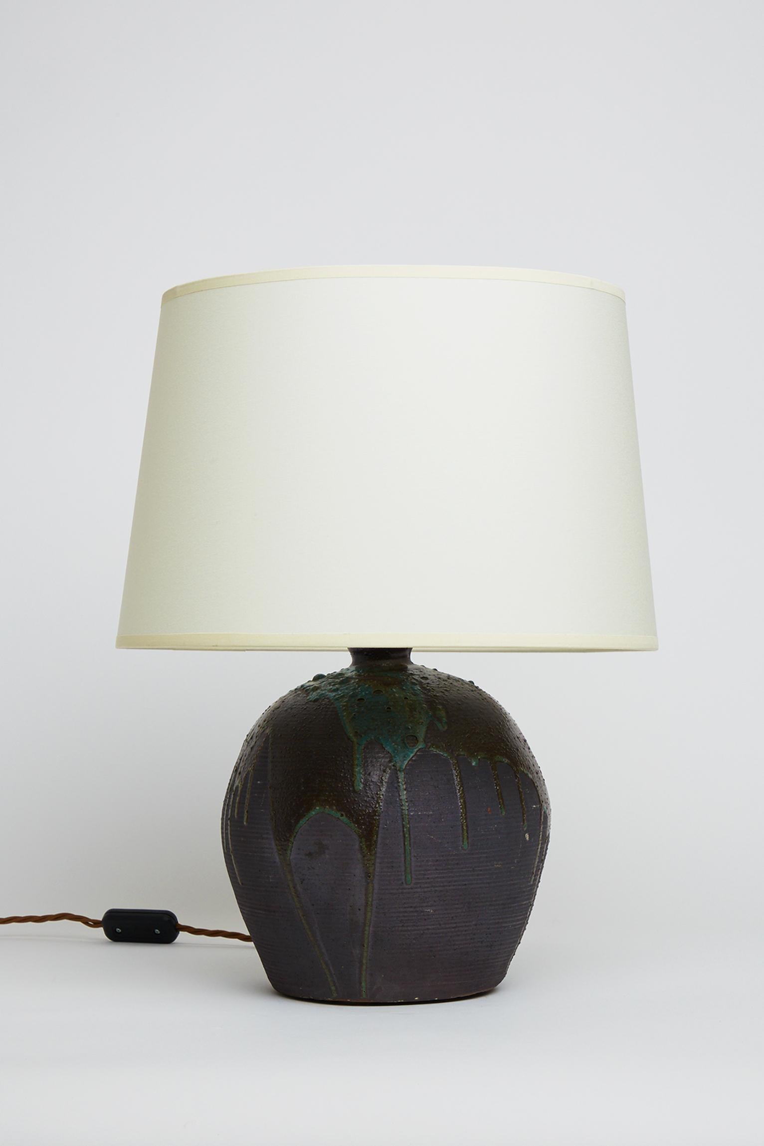 A pair of turned Puisaye stoneware table lamps, by Leon Pointu (1879-1942). Signature stamped. 
France, Circa 1920.
Measures: With the shade: 46.5 cm high by 35 cm diameter.
Lamp base only: 28 cm high by 21 cm diameter.