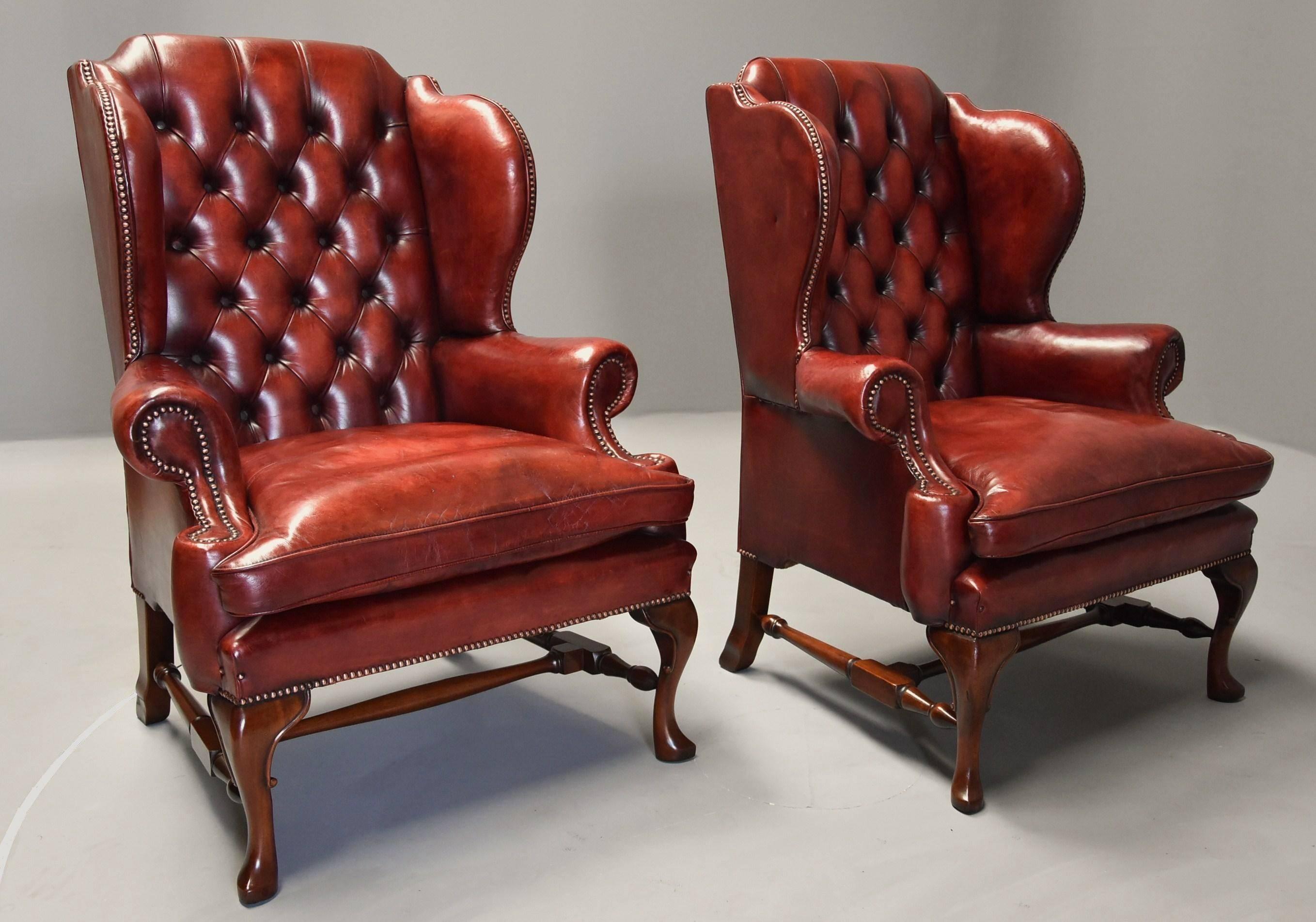 A superb pair of early 20th century Georgian style deep buttoned red leather wing armchairs.

These superb chairs each consist of a deep buttoned back with 'wings' to the top with a leather loose seat cushion, the chairs their retaining original
