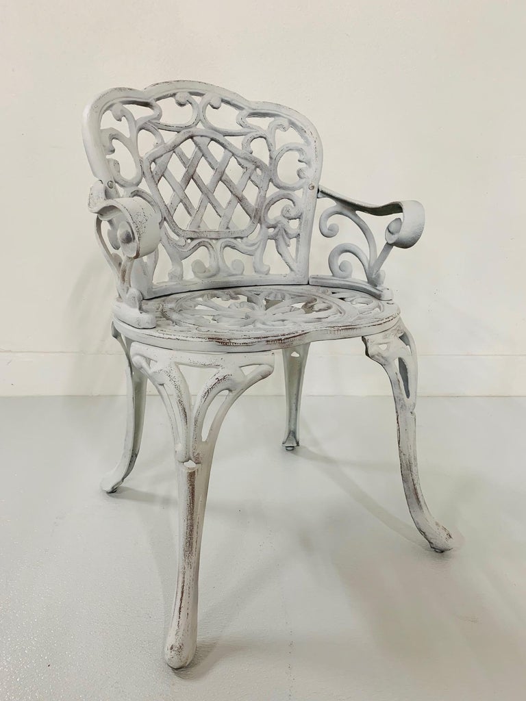 Pair of early cast iron garden armchairs. Painted white finish with a decorative pattern.