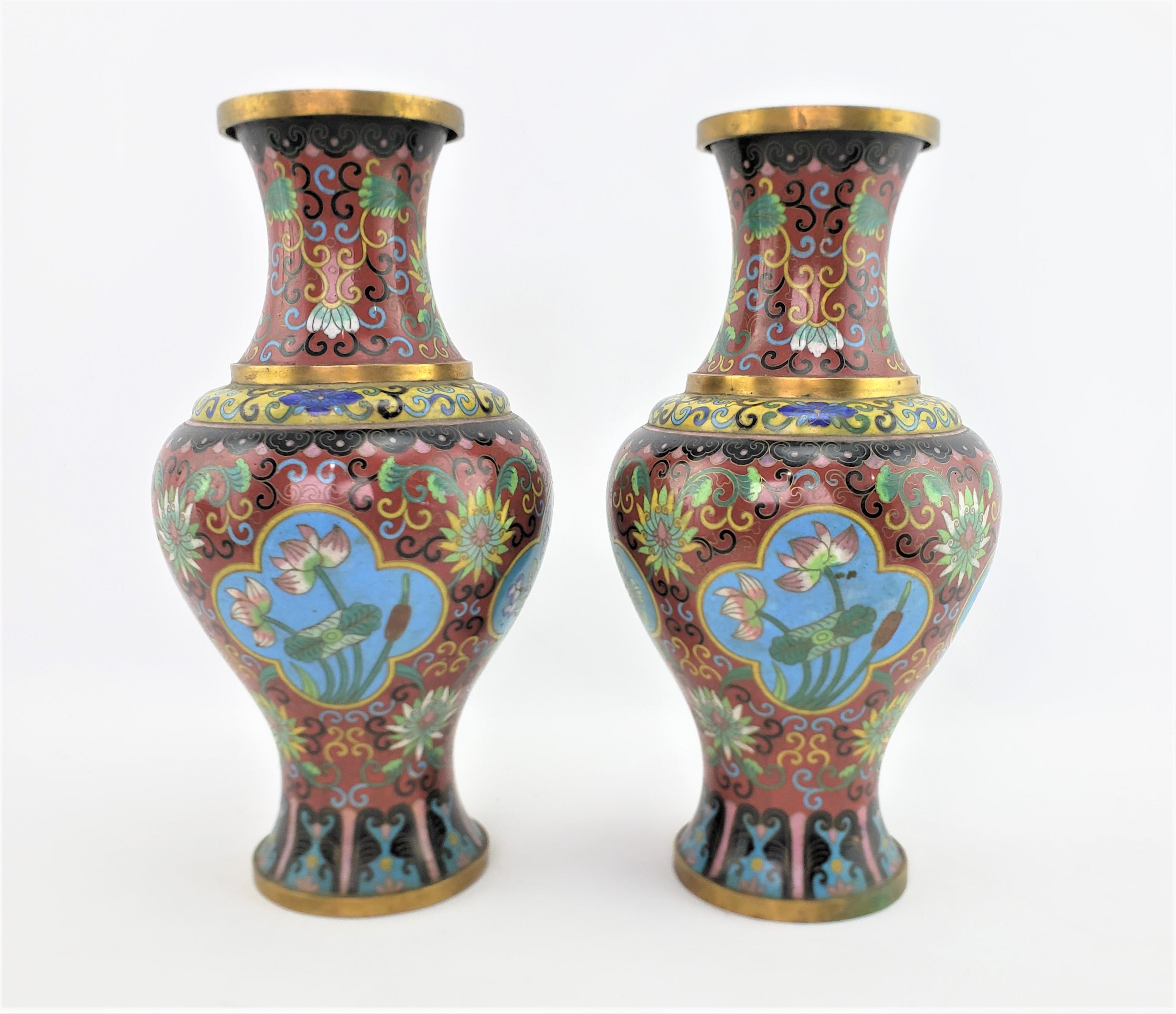 Dieses Paar antiker Cloisonné-Vasen stammt aus China aus der Zeit der frühen Republik und ist im chinesischen Exportstil gefertigt. Diese Vasen haben einen tief burgunderroten Hintergrund mit stilisierten und detaillierten Blumenpaneelen aus Nelken